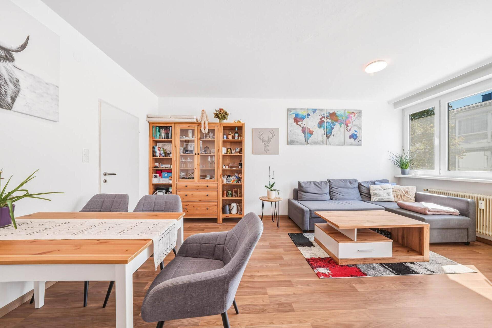 Heller Wohn- und Essbereich mit Holzboden, Esstisch und gemütlicher Sofaecke.