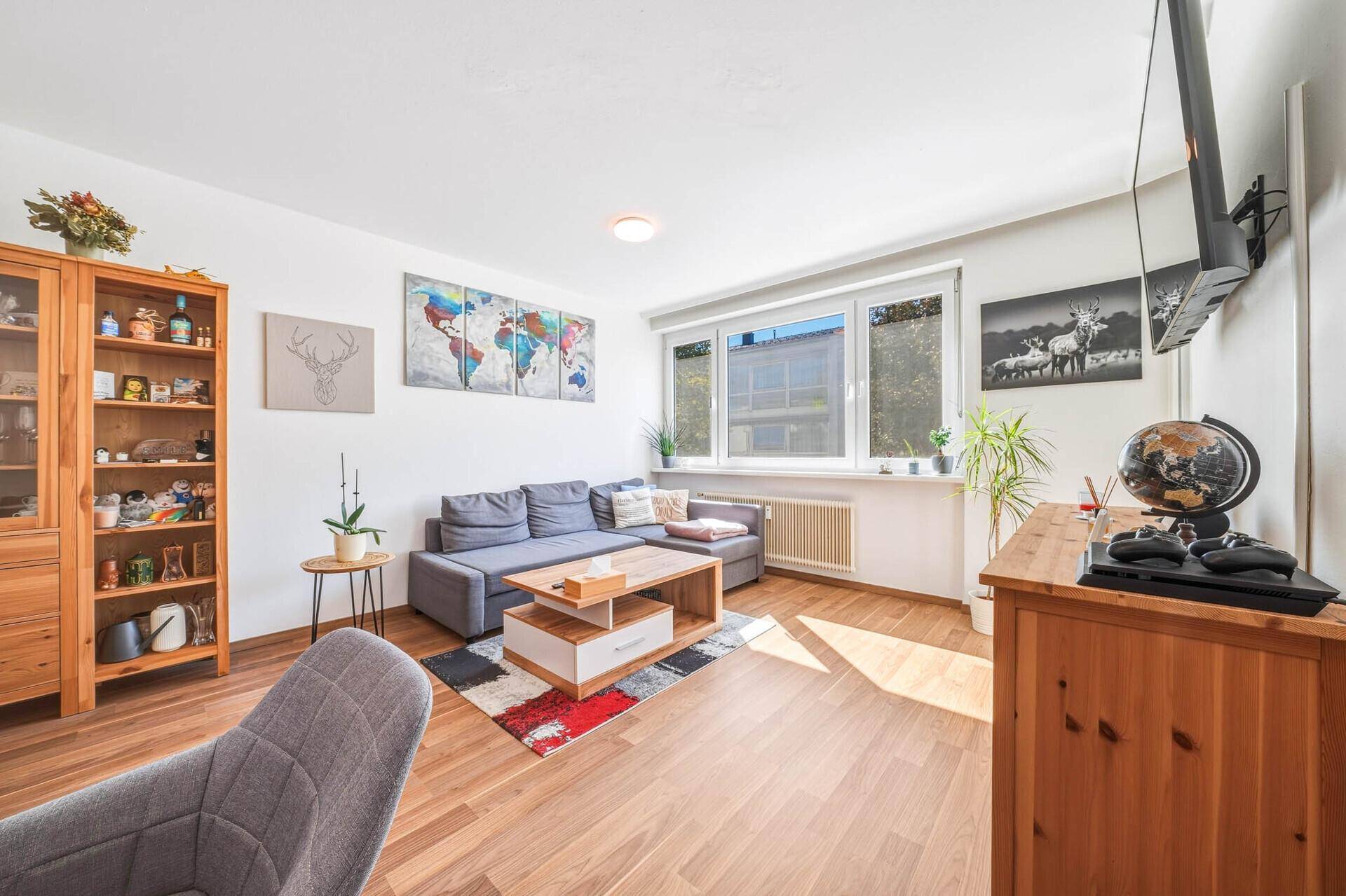 Geräumiges Wohnzimmer mit Holzboden, bequemer Sitzecke und einem großen Fenster für viel Licht.