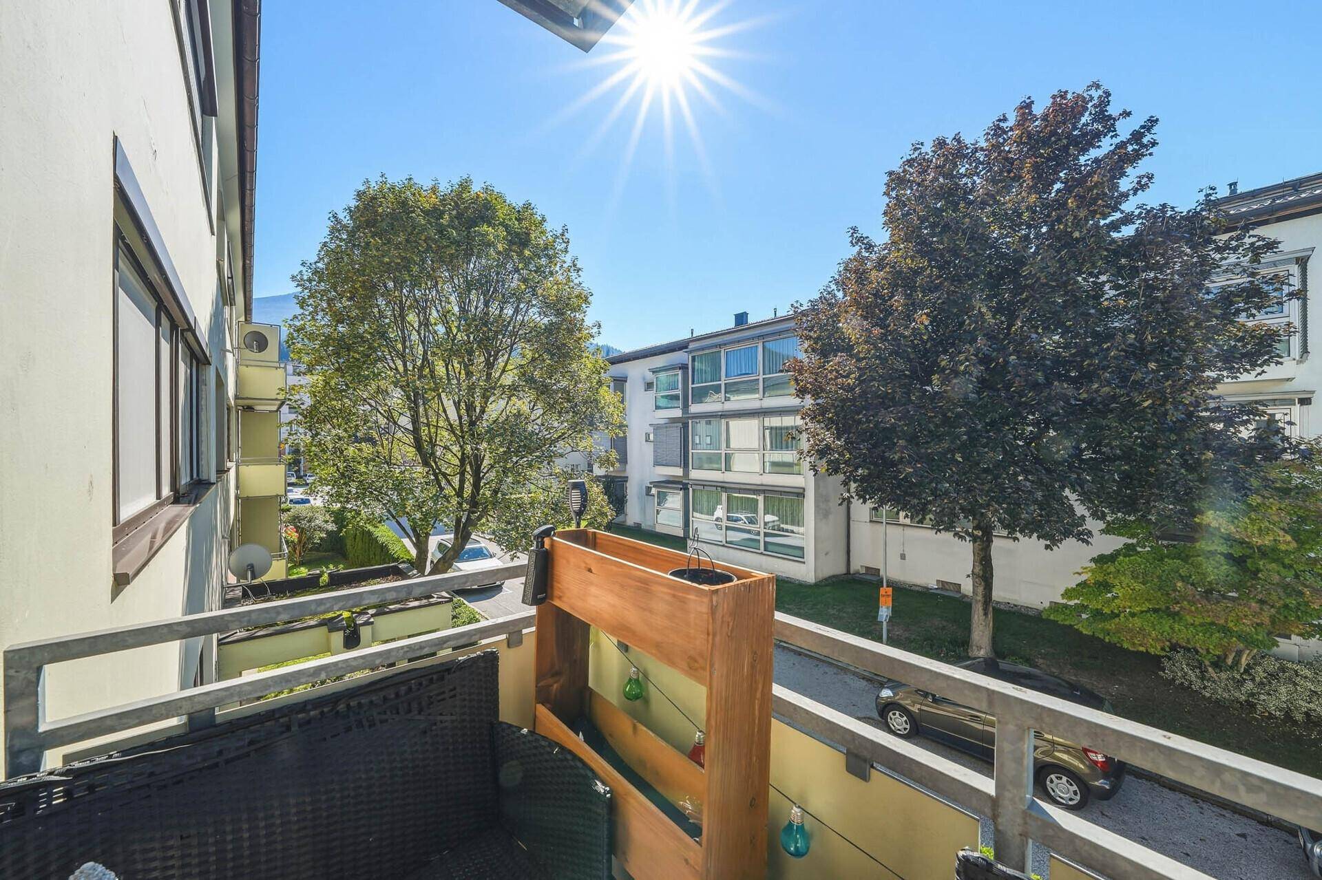 Sonniger Balkon mit Blick auf Bäume und die ruhige Straße, ideal zum Entspannen.
