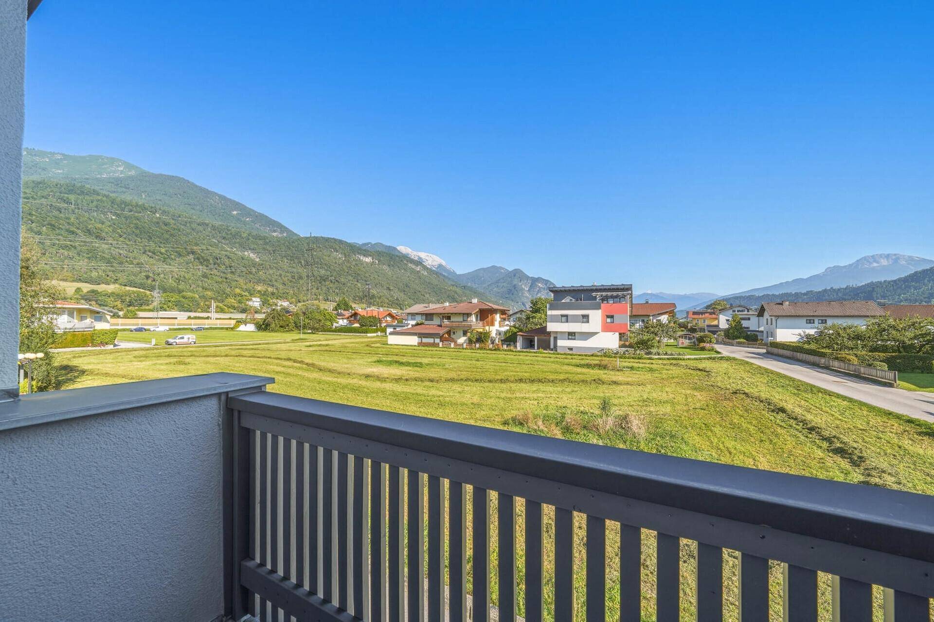 Weitläufiger Blick vom Balkon über grüne Wiesen und die majestätische Berglandschaft.