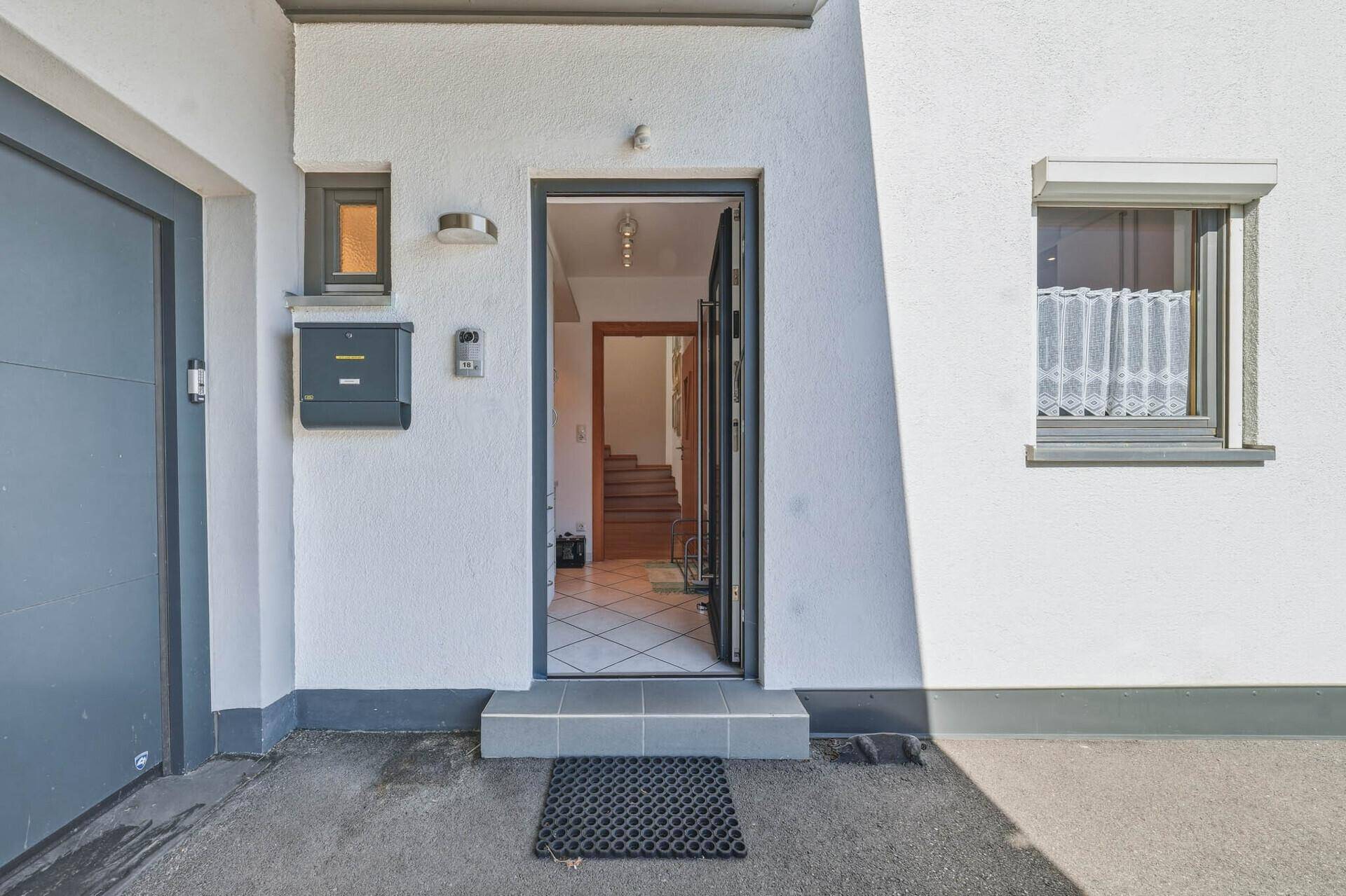 Hauseingang mit offener Tür, die einen Blick in den Flur und die Treppe freigibt.