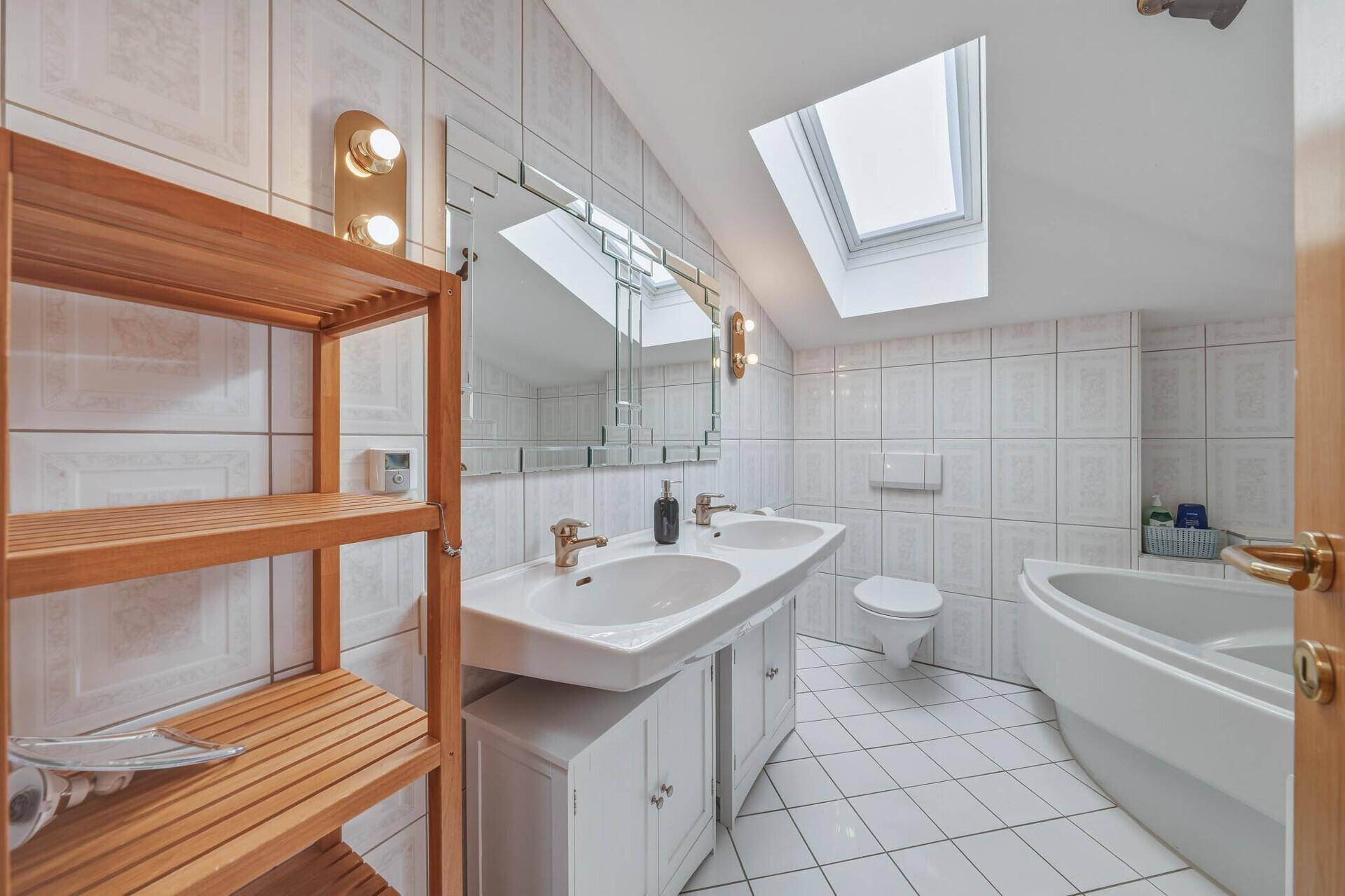 Geräumiges Badezimmer mit Doppelwaschbecken, Eckbadewanne und Dachfenster.