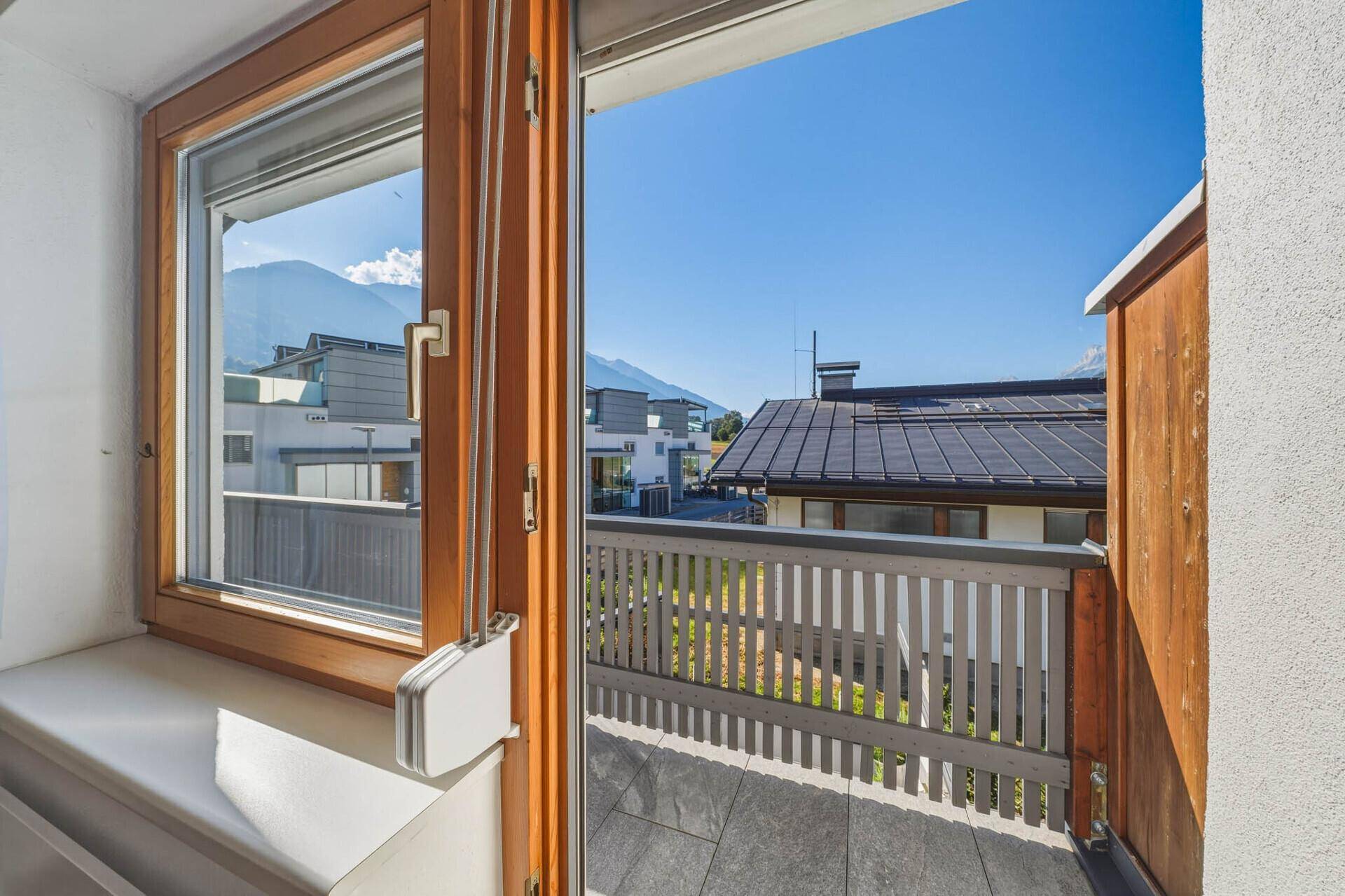 Blick vom Balkon auf die umliegenden Häuser und die beeindruckende Bergkulisse.