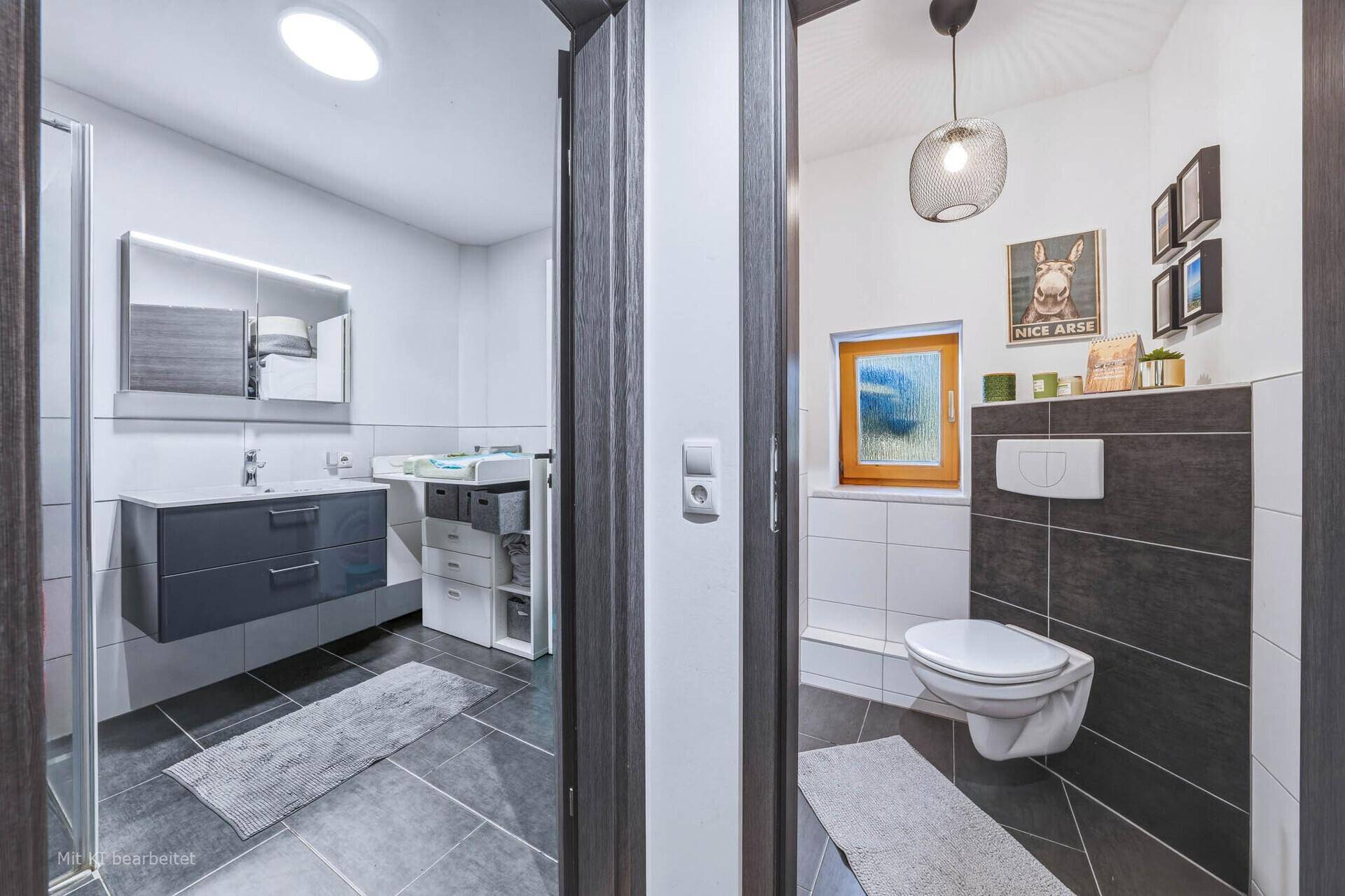 Flur mit Zugang zu einem modernen Badezimmer und einer separaten Gästetoilette.