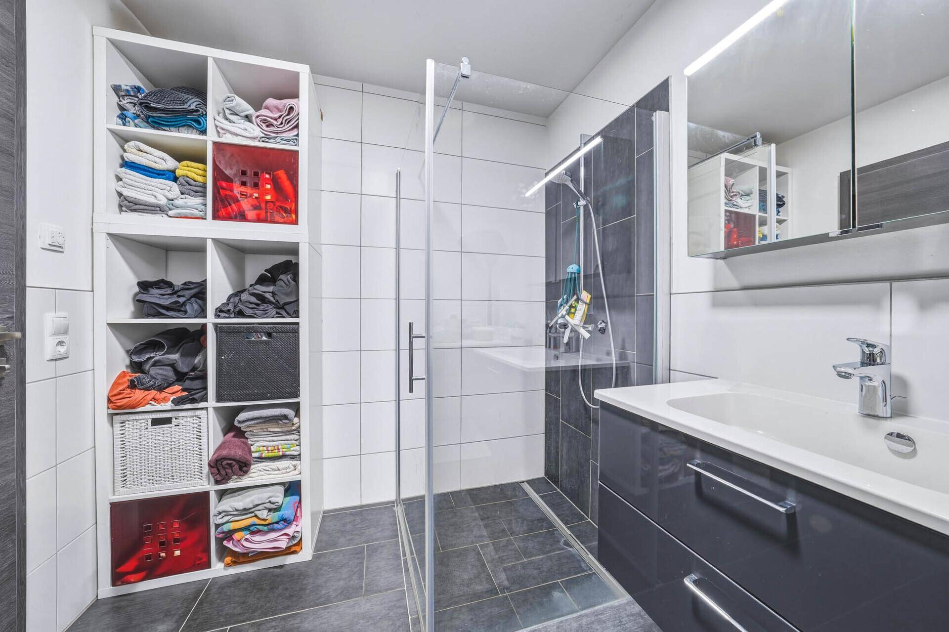 Helles Badezimmer mit moderner ebenerdiger Dusche und stilvollem Waschtisch mit Unterschrank.