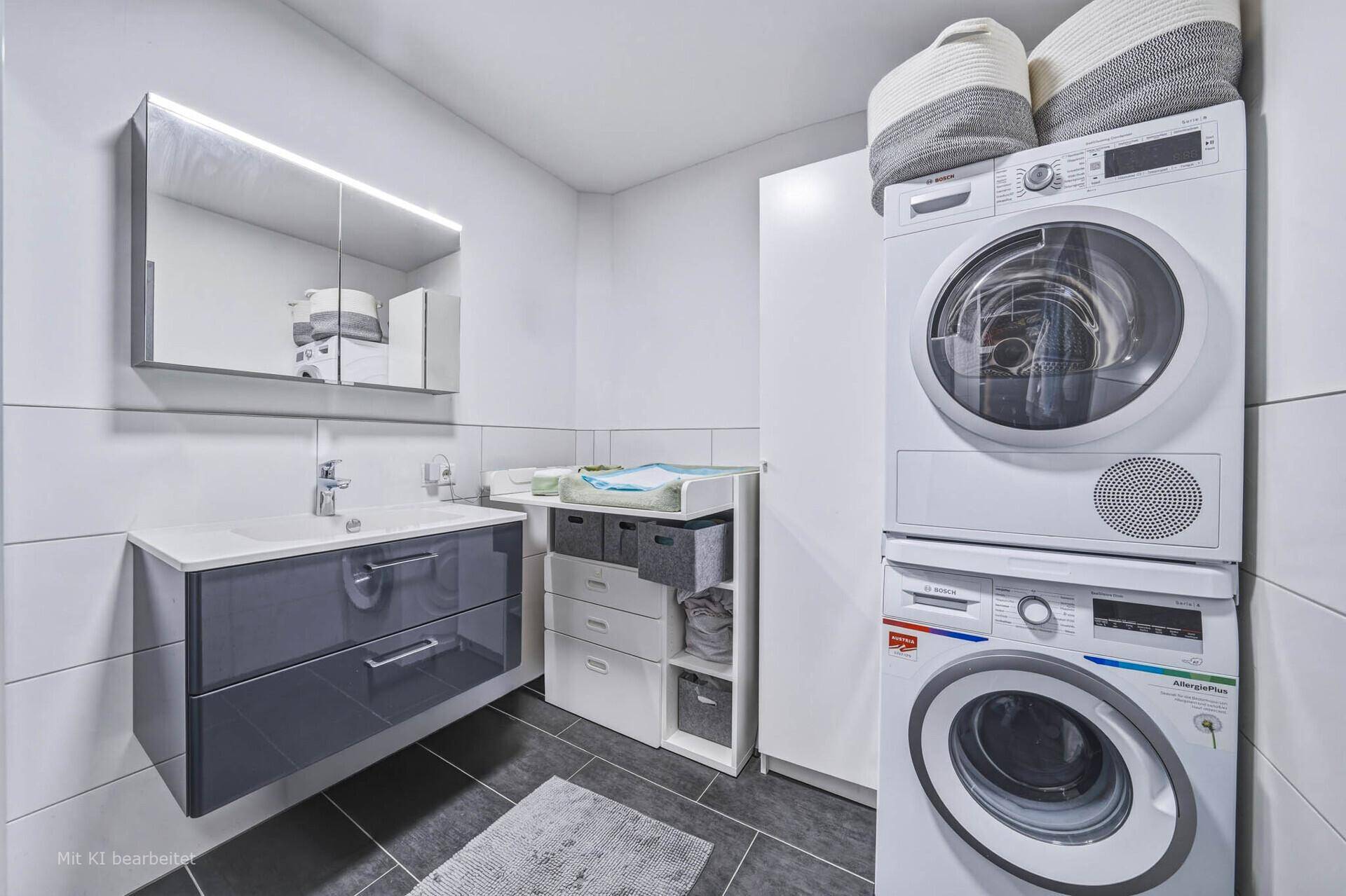 Funktionales Badezimmer mit Waschtisch, Spiegelschrank und integrierter Waschmaschine und Trockner.