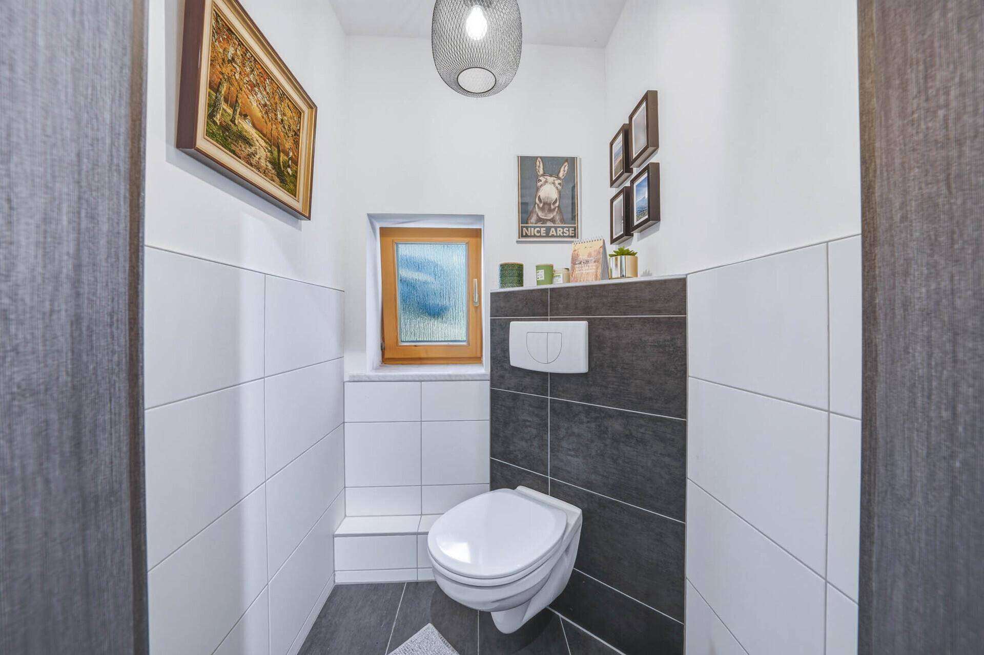 Separate Gästetoilette mit wandhängendem WC, Fenster und modernen Fliesen.