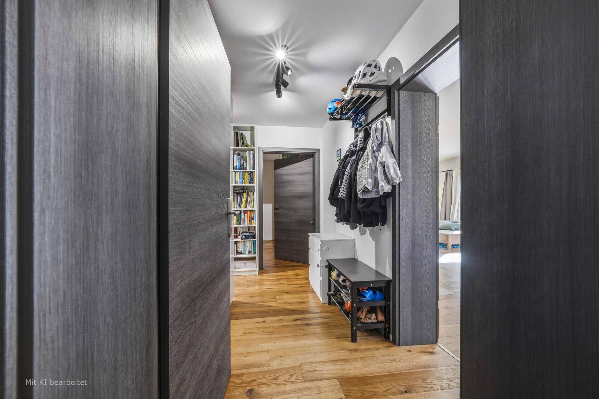 Langer Flur mit Garderobe und Bücherregal, der zu weiteren Zimmern im Haus führt.