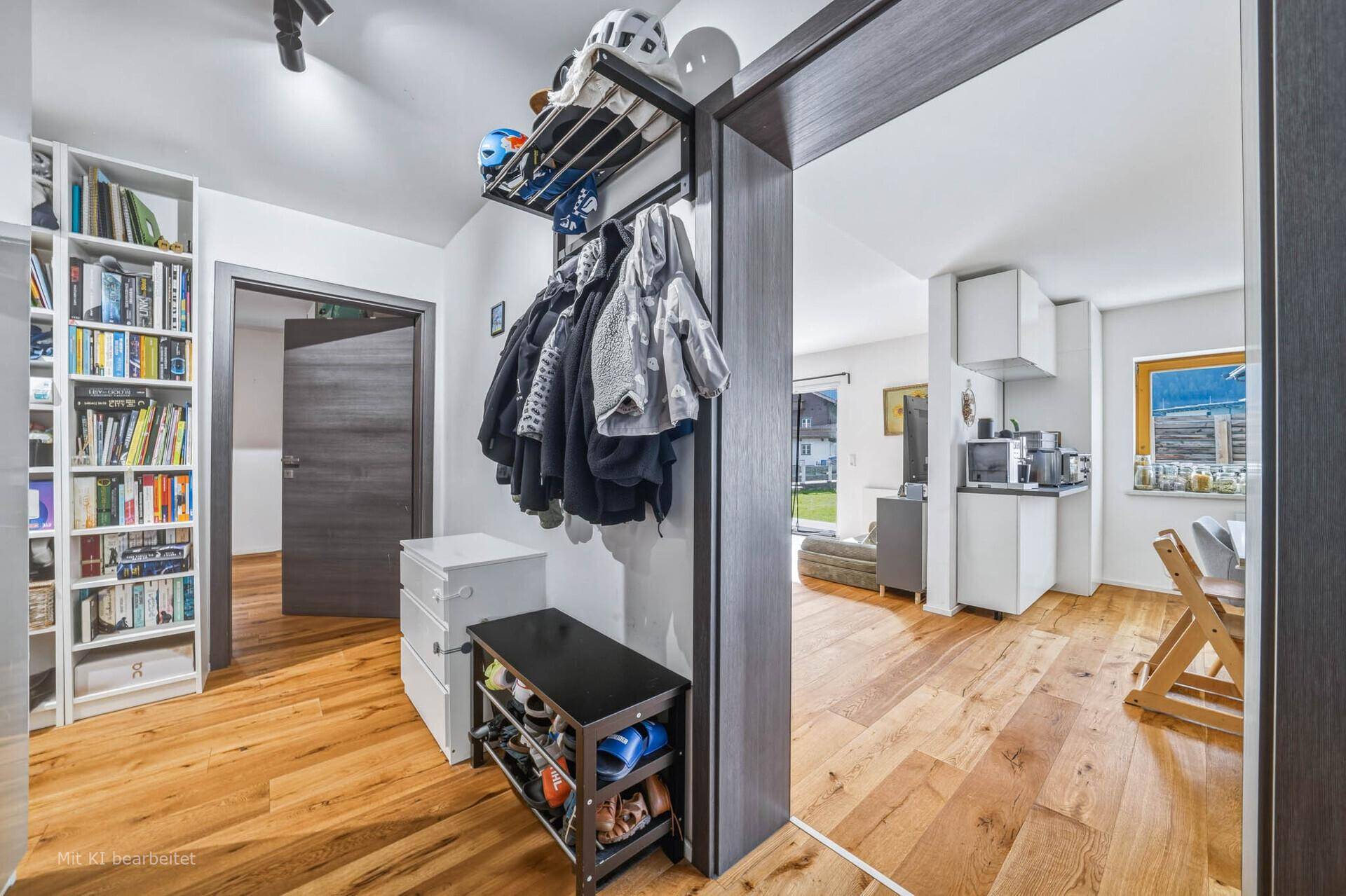Heller Flur mit Garderobe, Schuhregal und Bücherregal, der zu den Wohnbereichen führt.