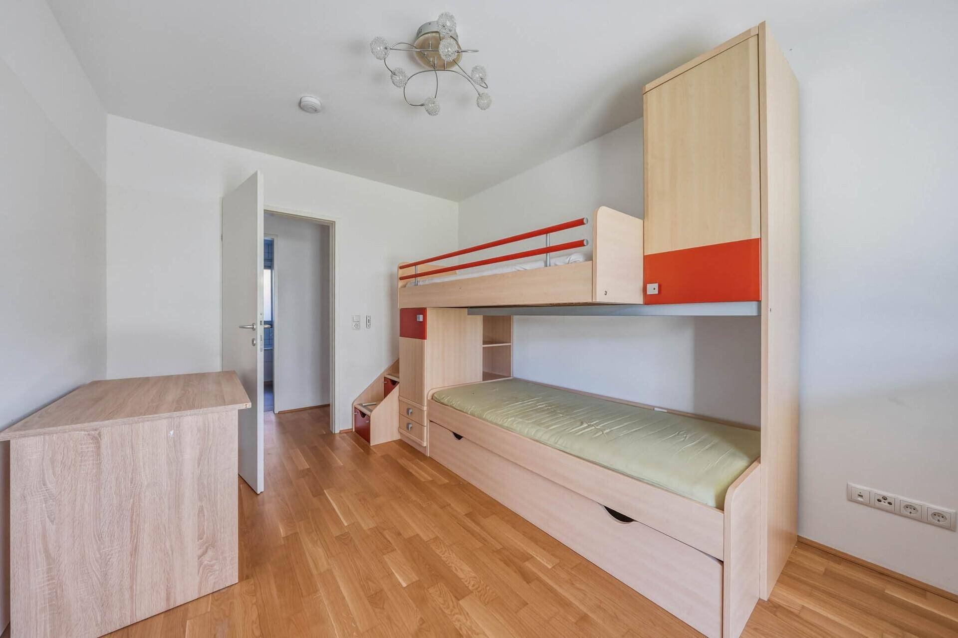 Kinderzimmer mit Etagenbett, Schreibtisch und Parkettboden, ideal für Geschwister.