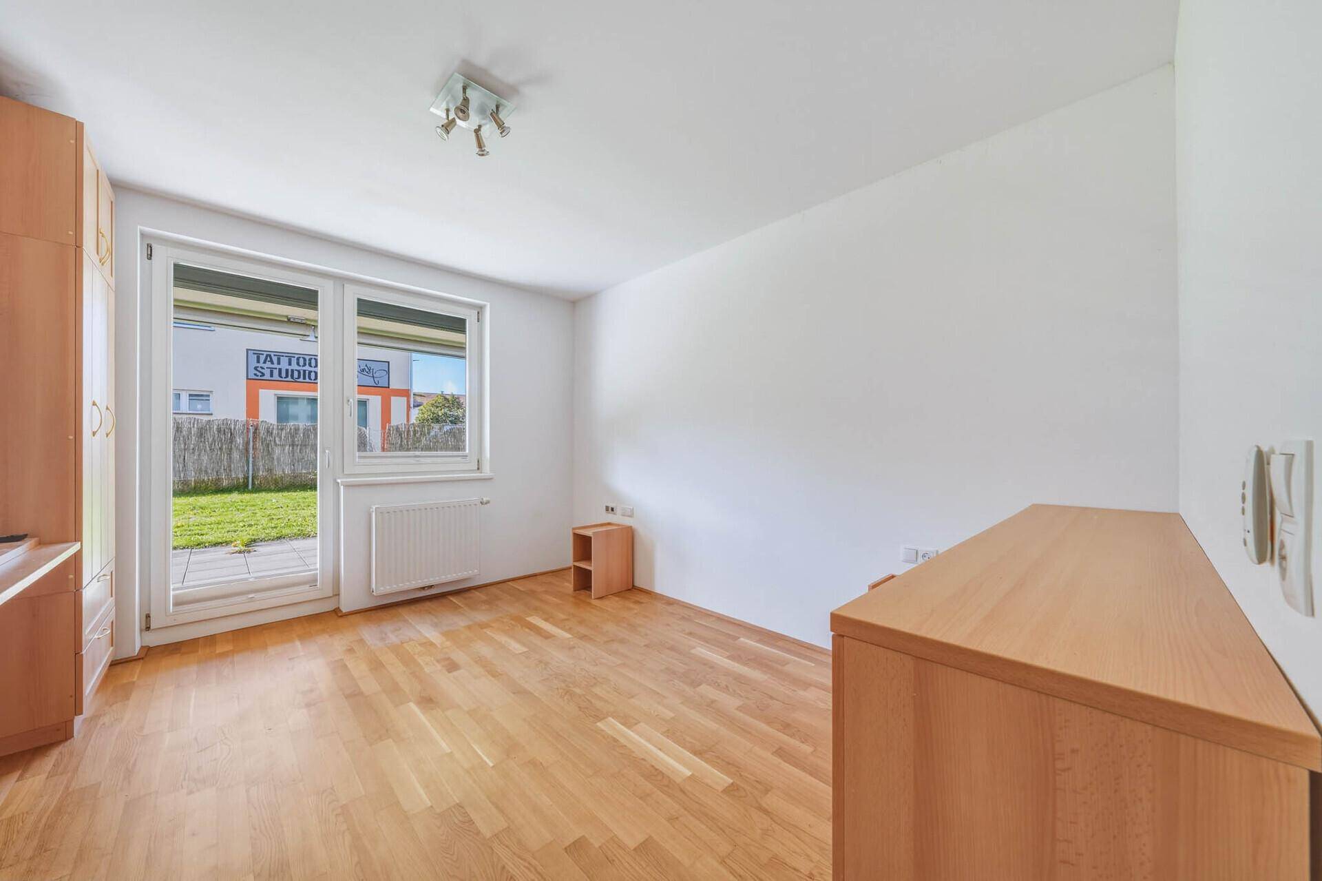 Helles Schlafzimmer mit Parkettboden und direktem Zugang zum privaten Gartenbereich.