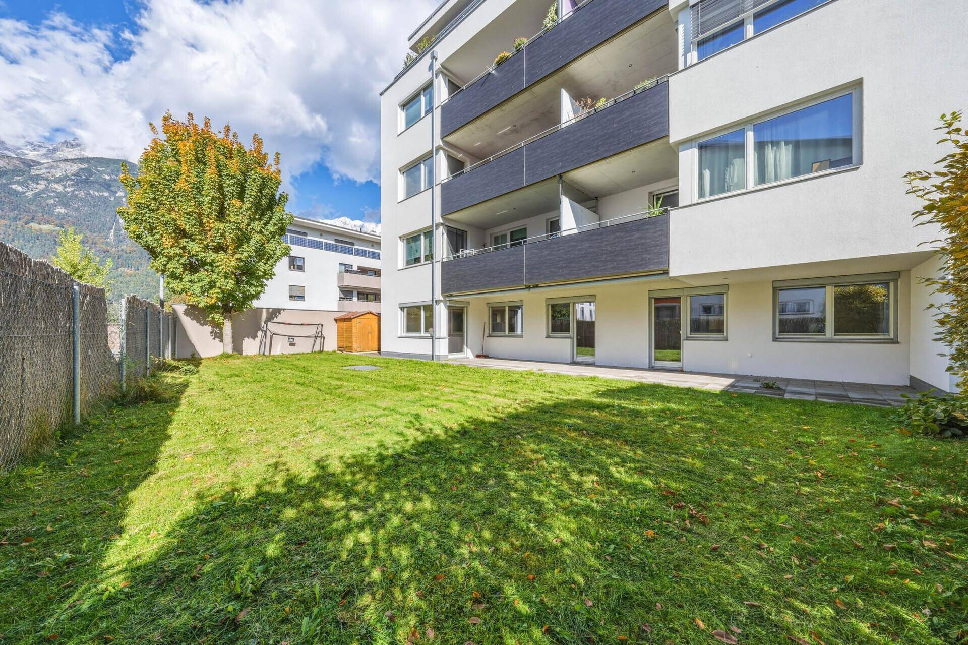 Weitläufige Rasenfläche vor dem Gebäude mit Bergblick und sonniger Lage.