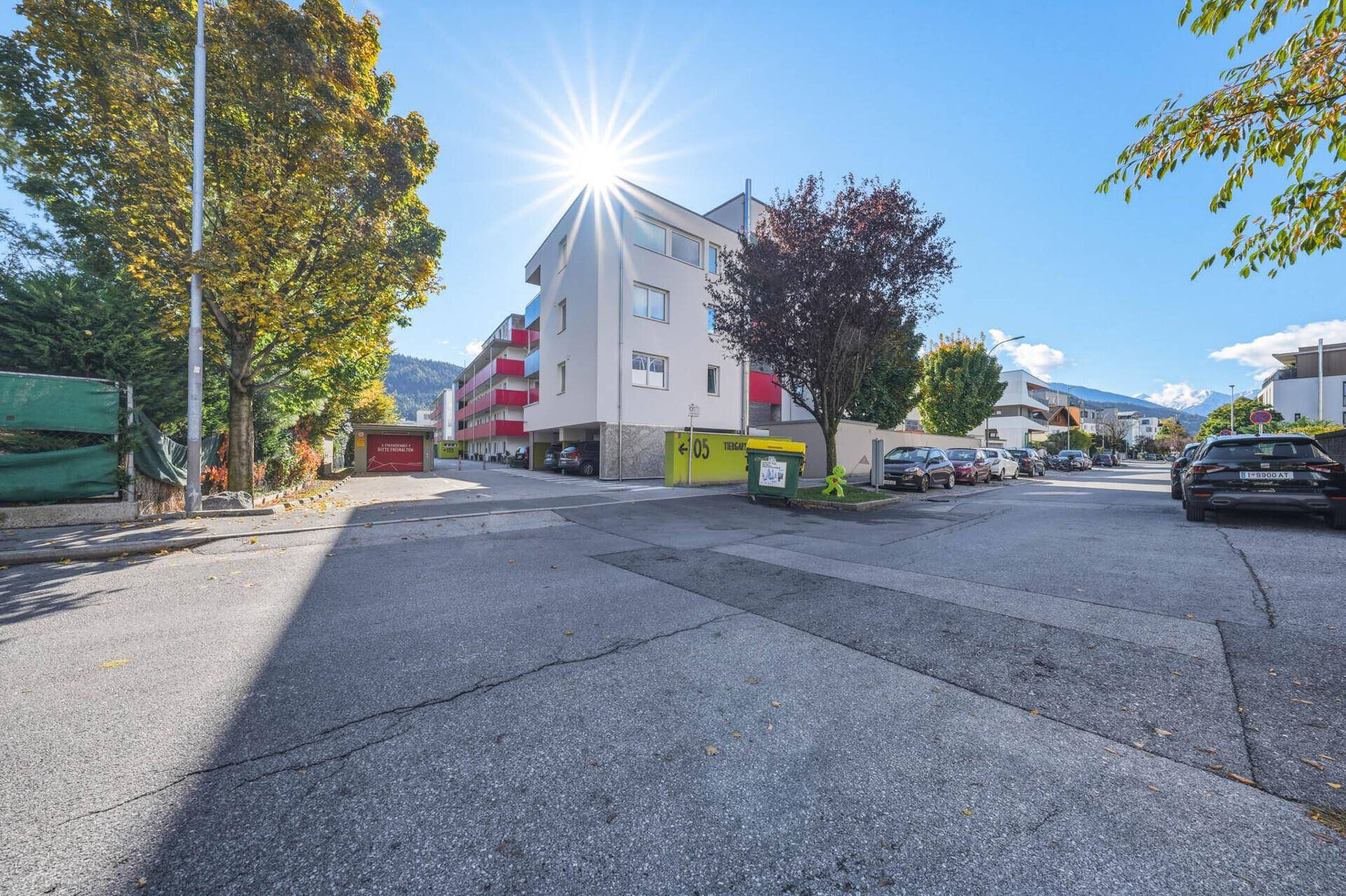 Modernes Wohngebäude an einer Straße mit Bäumen und sonnigem Wetter.