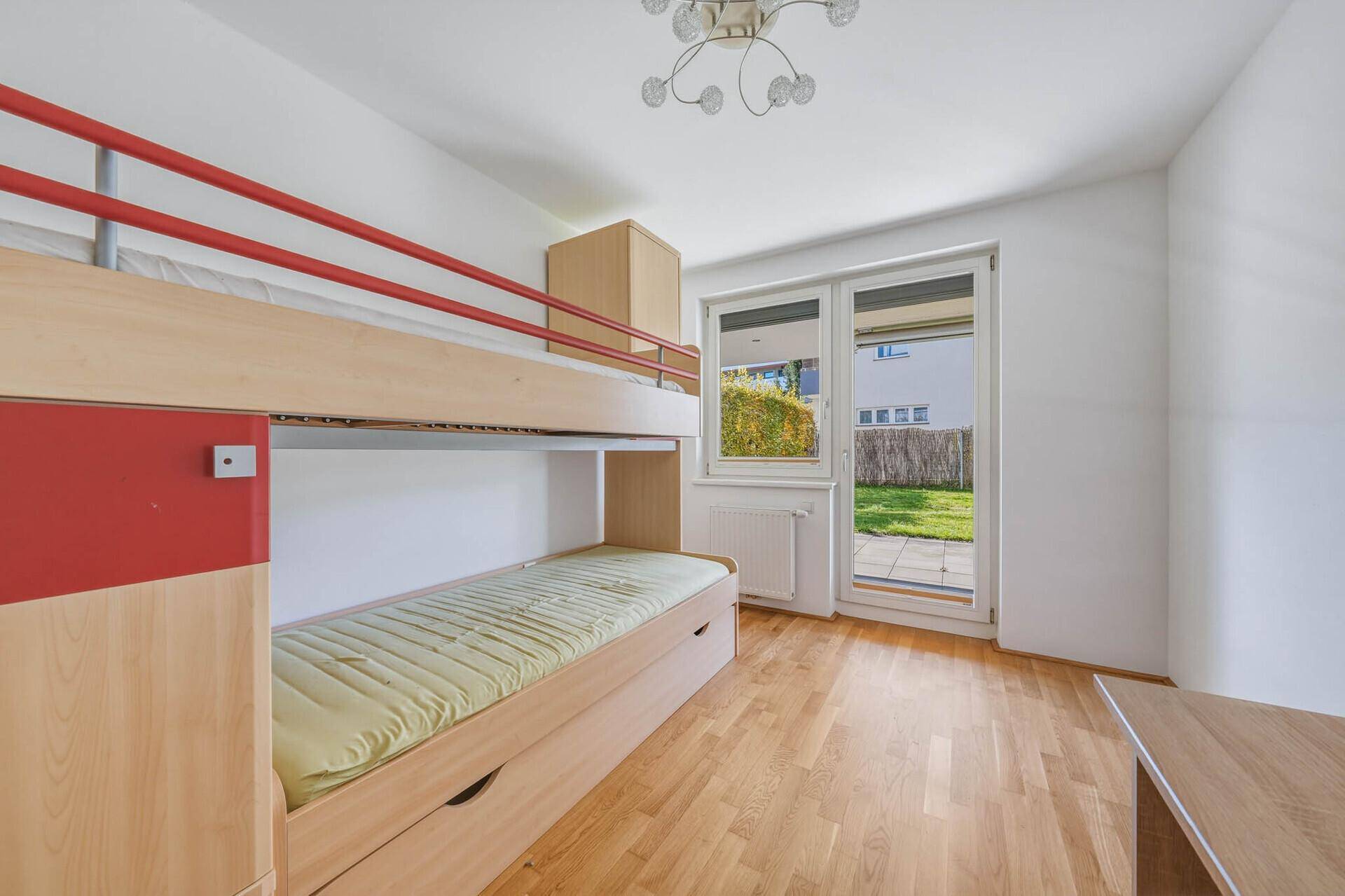 Kinderzimmer mit Etagenbett und Zugang zum Garten durch eine Fenstertür.