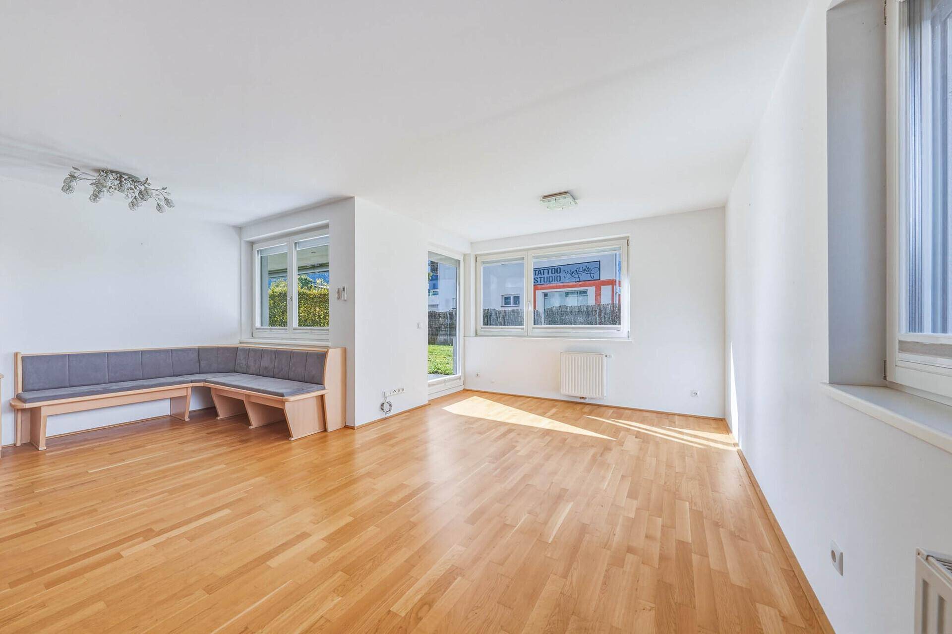 Geräumiges Wohnzimmer mit Parkettboden, großen Fenstern und Zugang zum Gartenbereich.