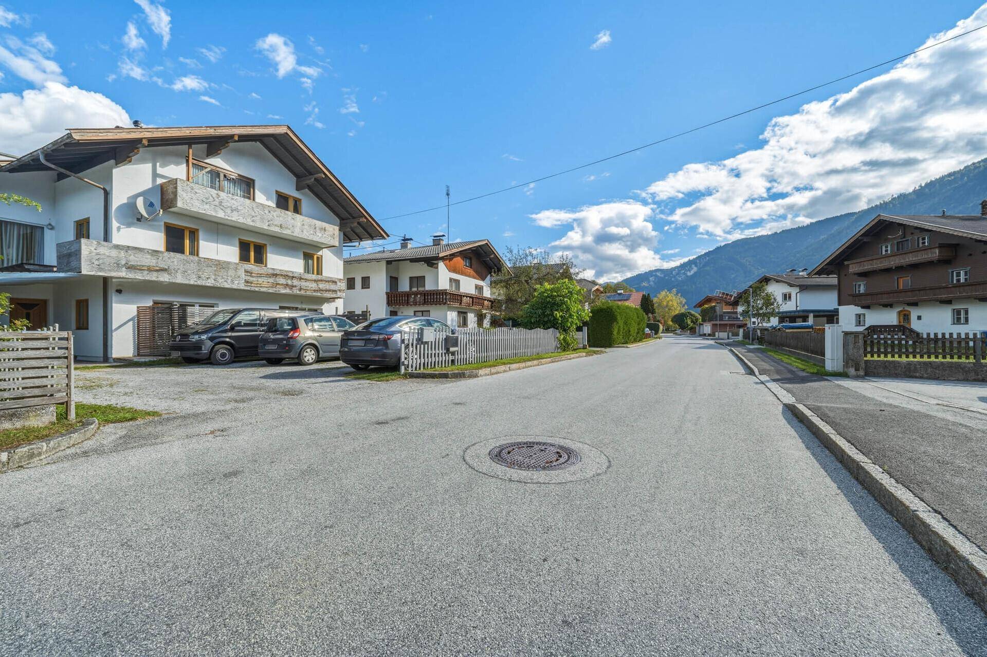 Weitläufige Wohnstraße mit gepflegten Häusern und freiem Blick auf die Berglandschaft.