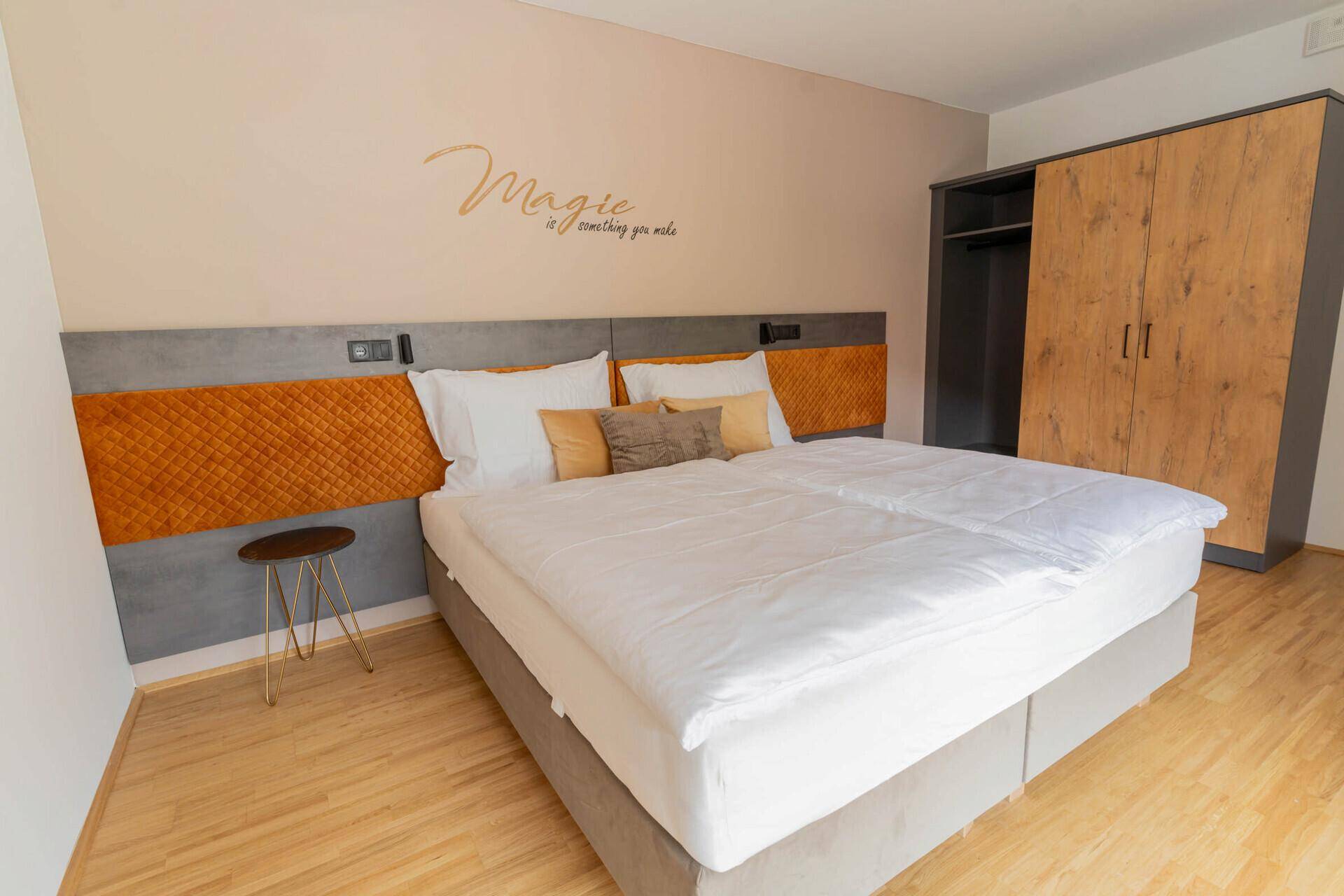 Gemütliches Schlafzimmer mit Doppelbett, Holzboden und dekorativer Wandgestaltung.