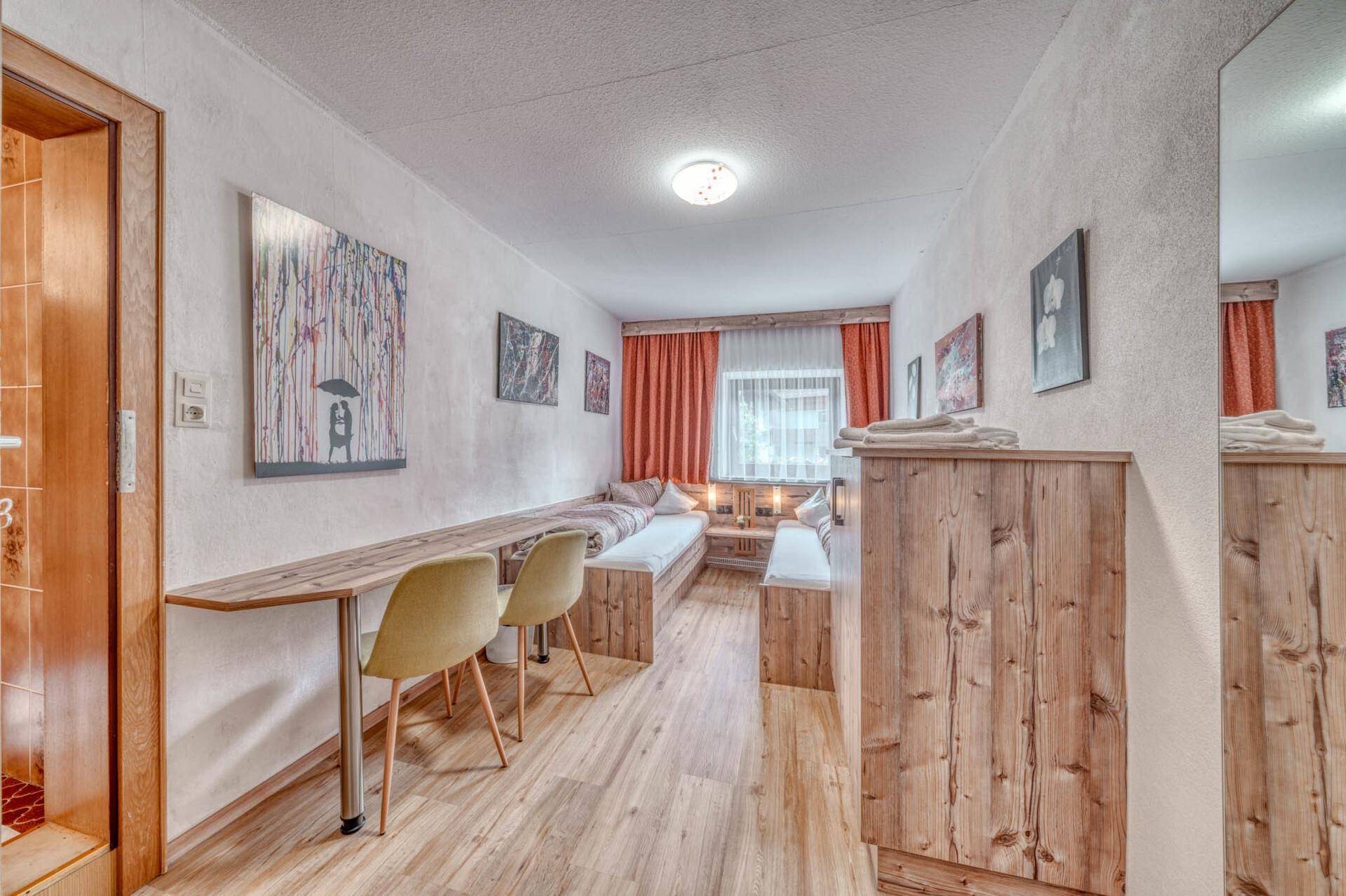 Helles Schlafzimmer mit zwei Einzelbetten, Schreibtisch und Holzboden, praktisch eingerichtet.
