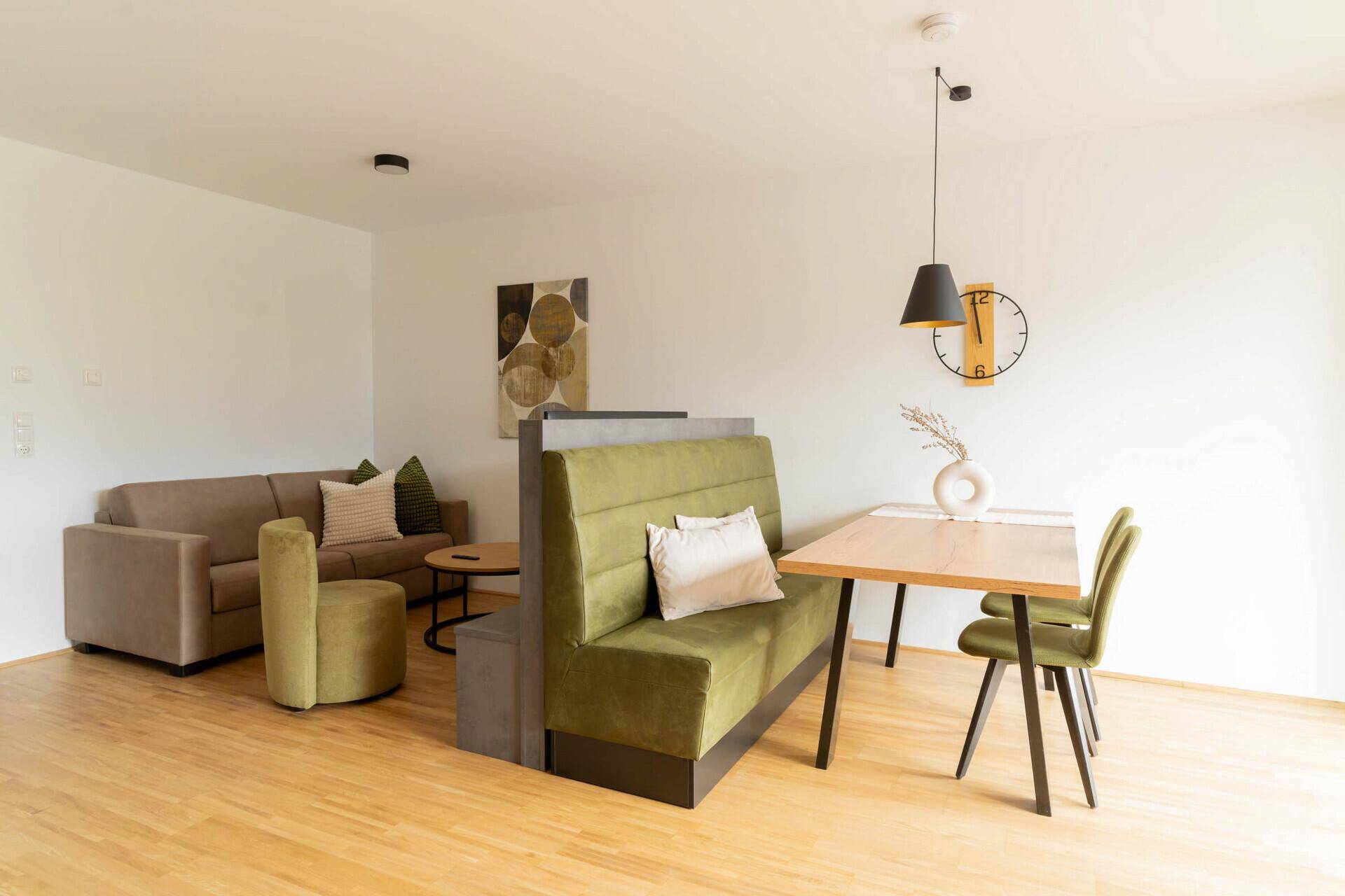 Heller Wohn-Essbereich mit Holzboden, Esstisch und gemütlicher Sitzecke.