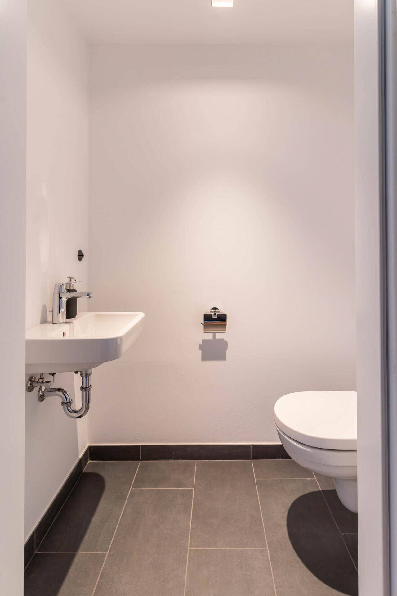 Heller Eingangsbereich mit Holzboden, Garderobenschrank und ovalem Wandspiegel.