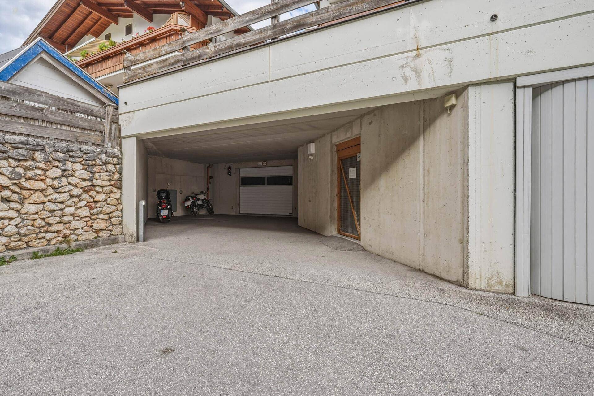 Geräumige Tiefgarage mit Betonwänden und -decke, bietet Platz für Fahrzeuge und Motorräder.