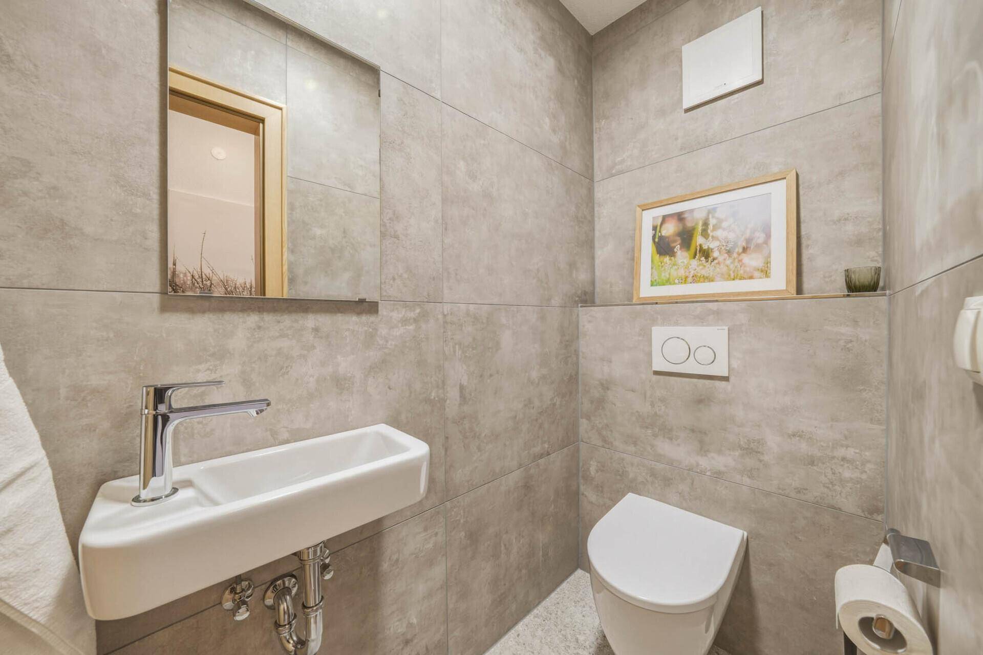 Modernes Gäste-WC mit kleinem Waschbecken und wandhängender Toilette.