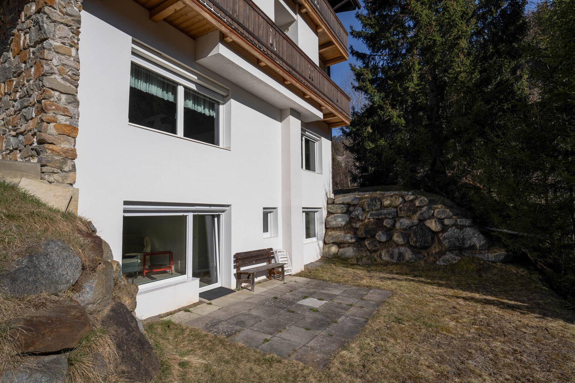 Kleine Terrasse im Erdgeschoss mit Sitzbank und Blick ins Grüne.