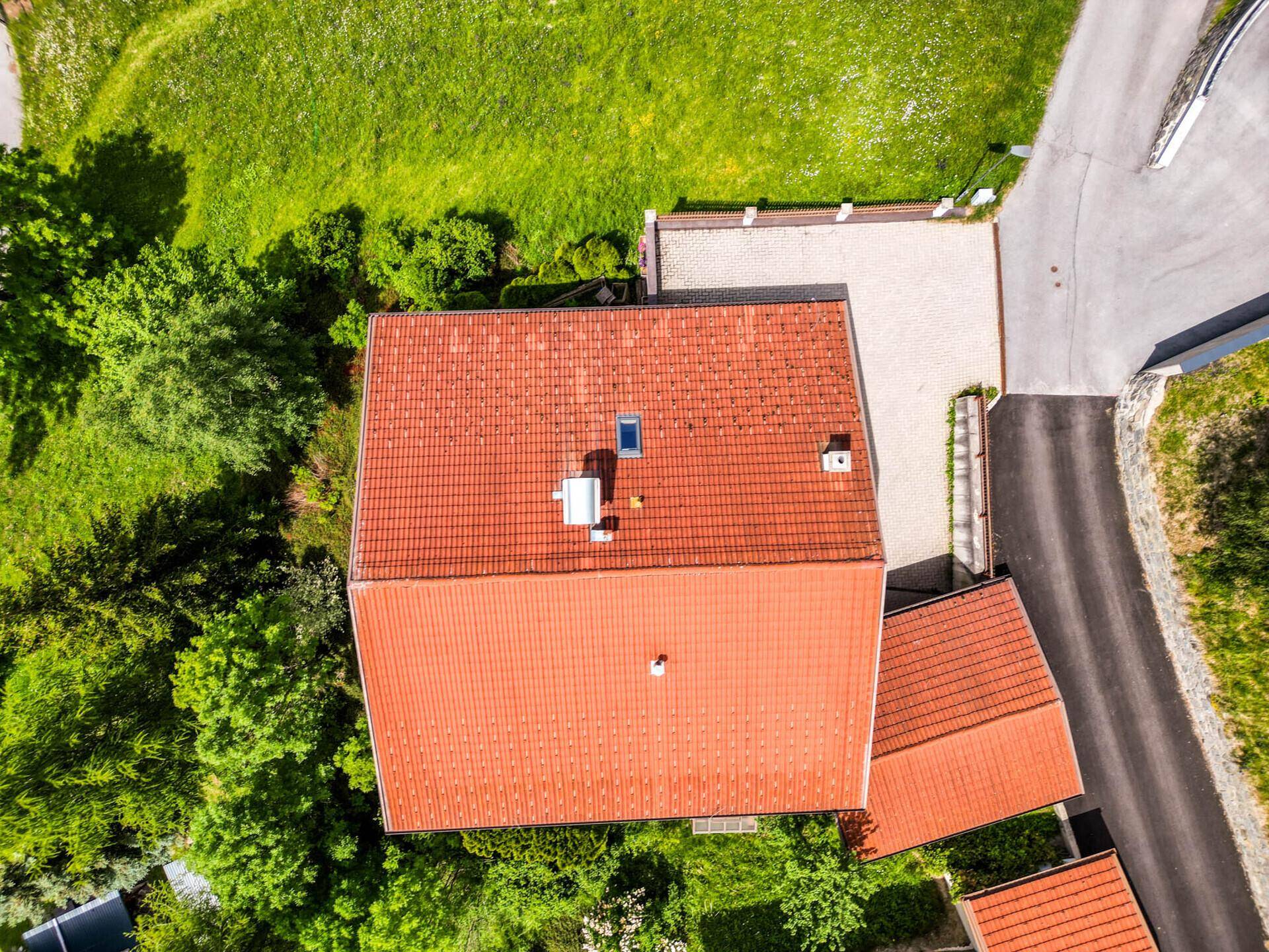 Luftaufnahme des Daches und des gepflasterten Parkplatzes, umgeben von Bäumen und Wegen.
