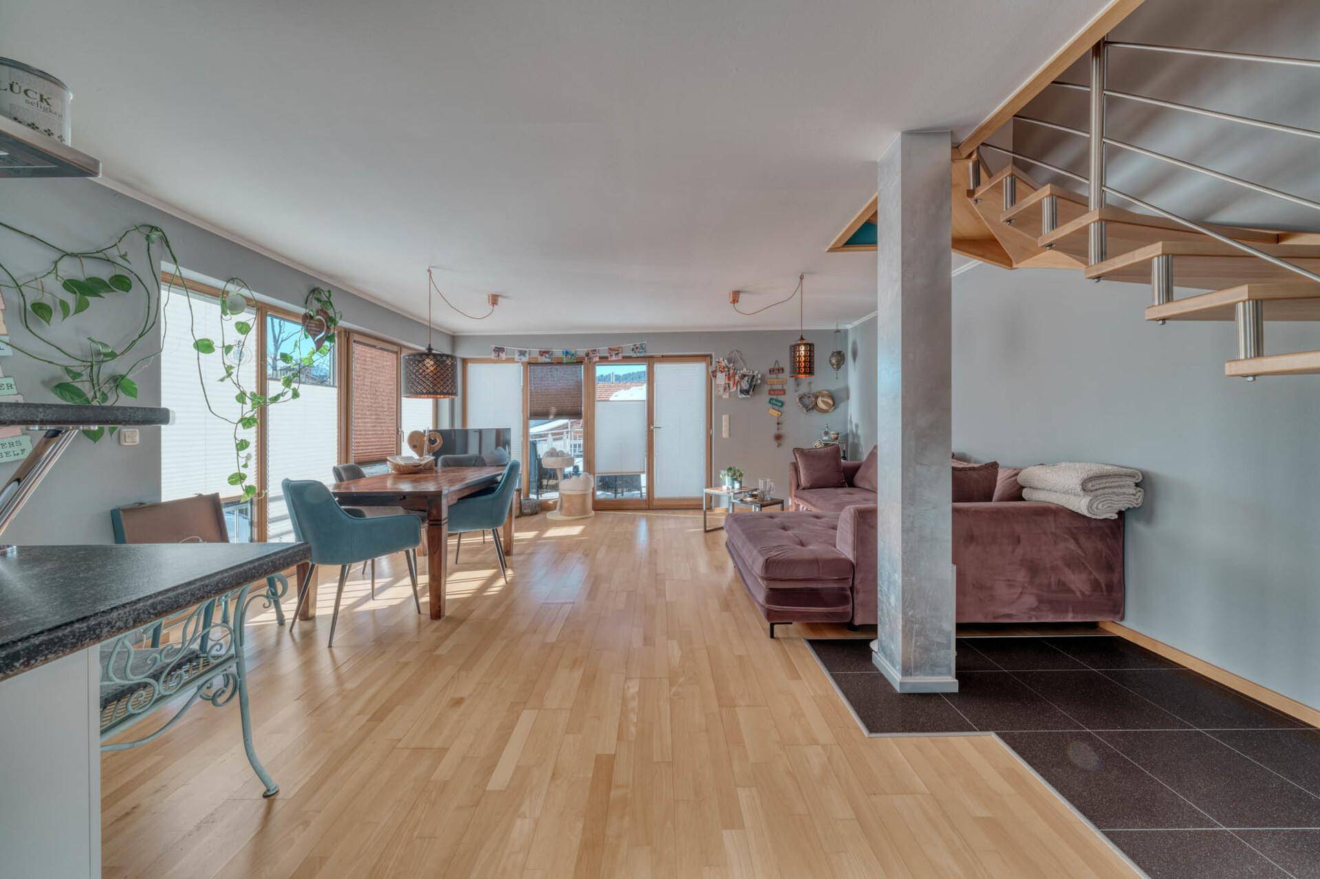 Heller Wohn- und Essbereich mit Holzboden, bequemer Couch und Zugang zur Terrasse.