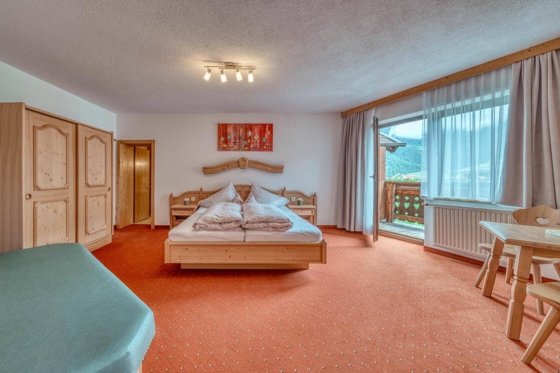 Helles Schlafzimmer mit traditionellen Holzmöbeln und Zugang zum Balkon.