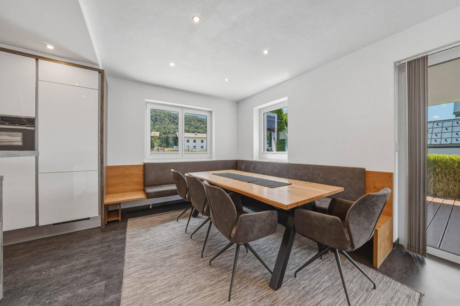 Moderner Essbereich mit Holztisch und Eckbank, integriert in einen offenen Wohnraum mit Küchenzugang.