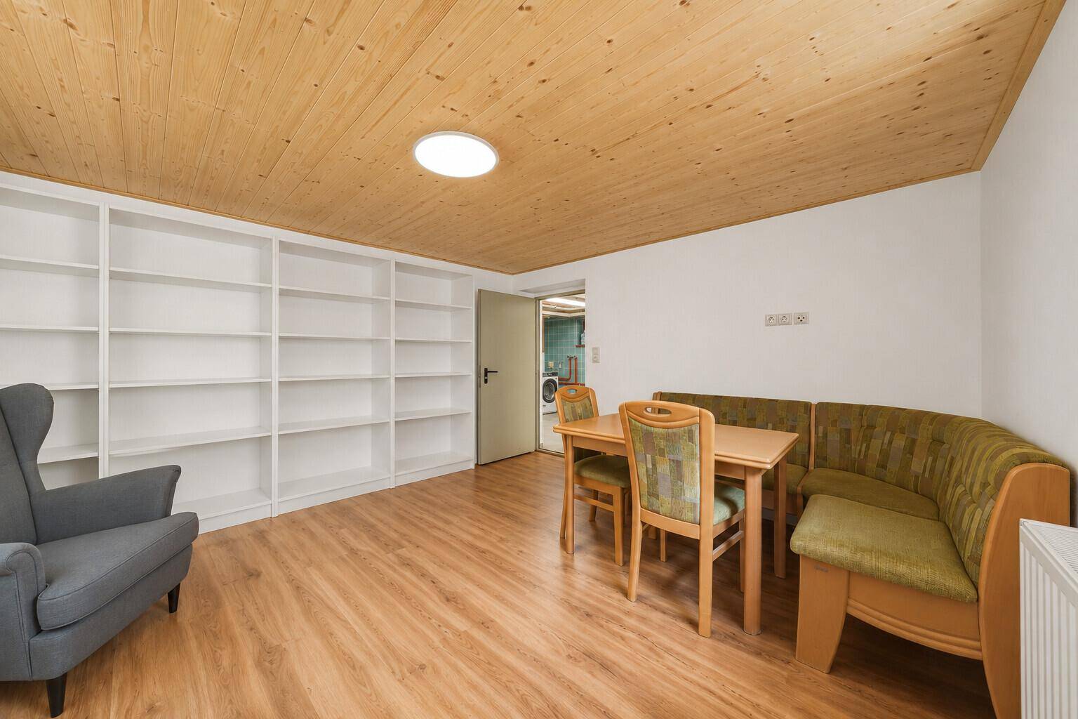 Gemütlicher Wohn-Essbereich mit Holzdecke, Einbauregalen und rustikalen Sitzmöbeln.