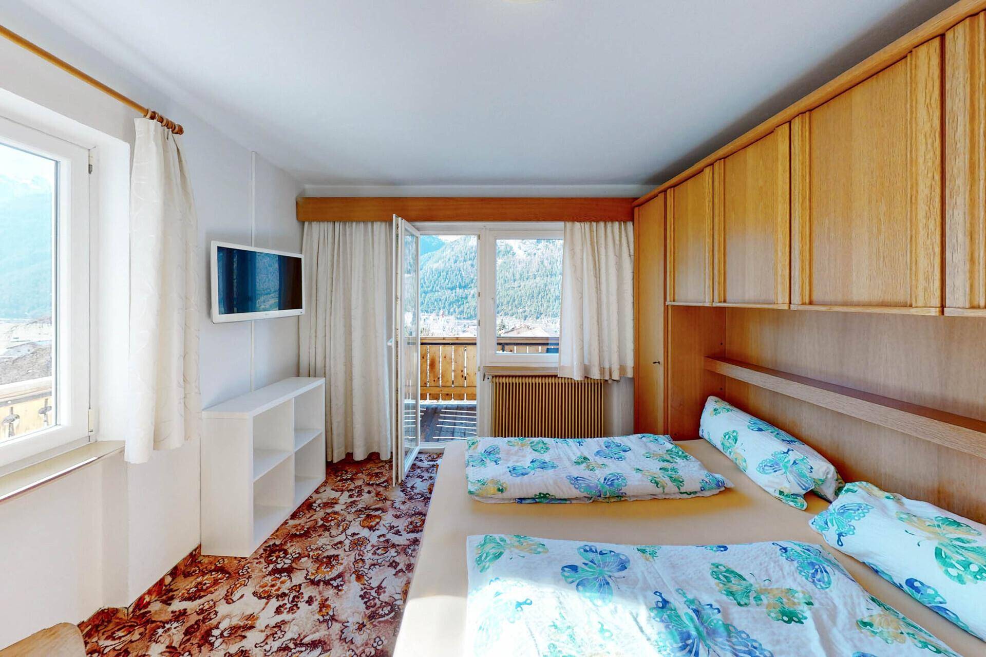 Schlafzimmer mit Doppelbett, Einbauschränken und Balkonzugang.