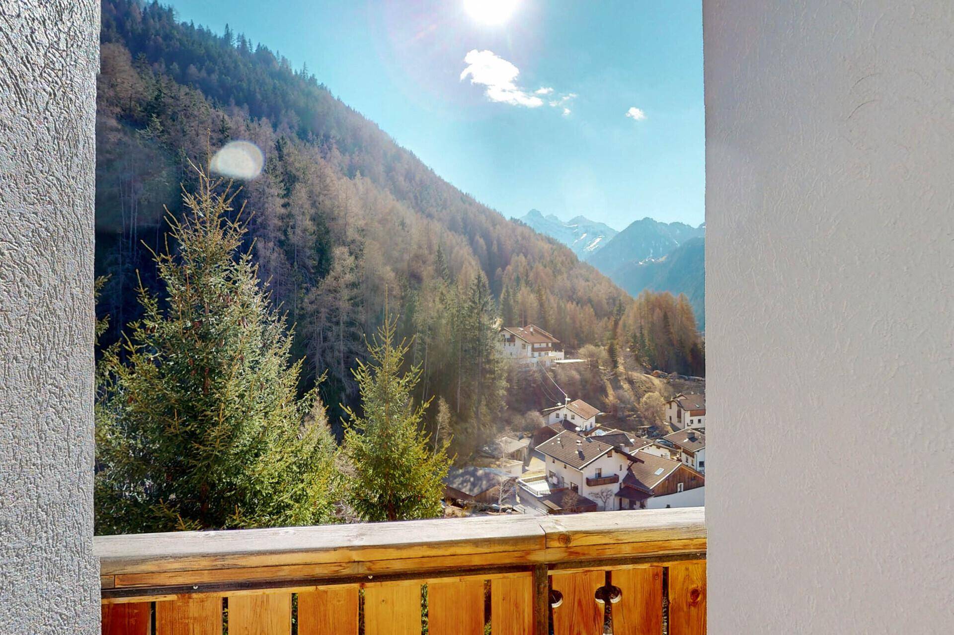 Sonniger Balkon mit Blick auf die bewaldeten Berge und das Tal.