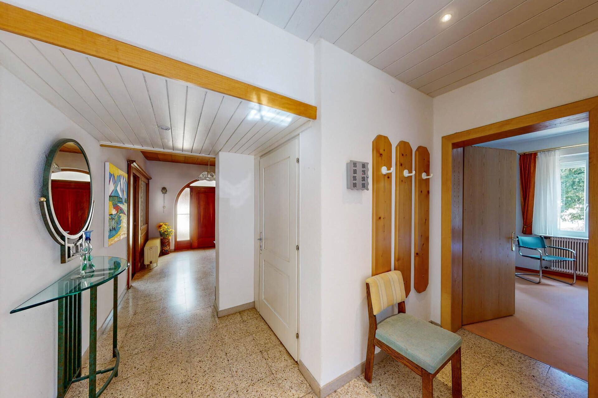 Freundlicher Flur mit Terrazzoboden, Garderobe und Zugang zu weiteren Räumen.