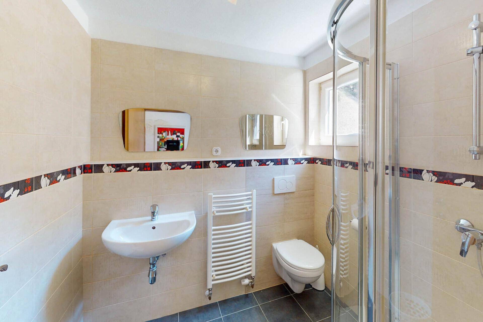 Modernes Badezimmer mit Duschkabine, WC, Waschbecken und beheiztem Handtuchhalter.