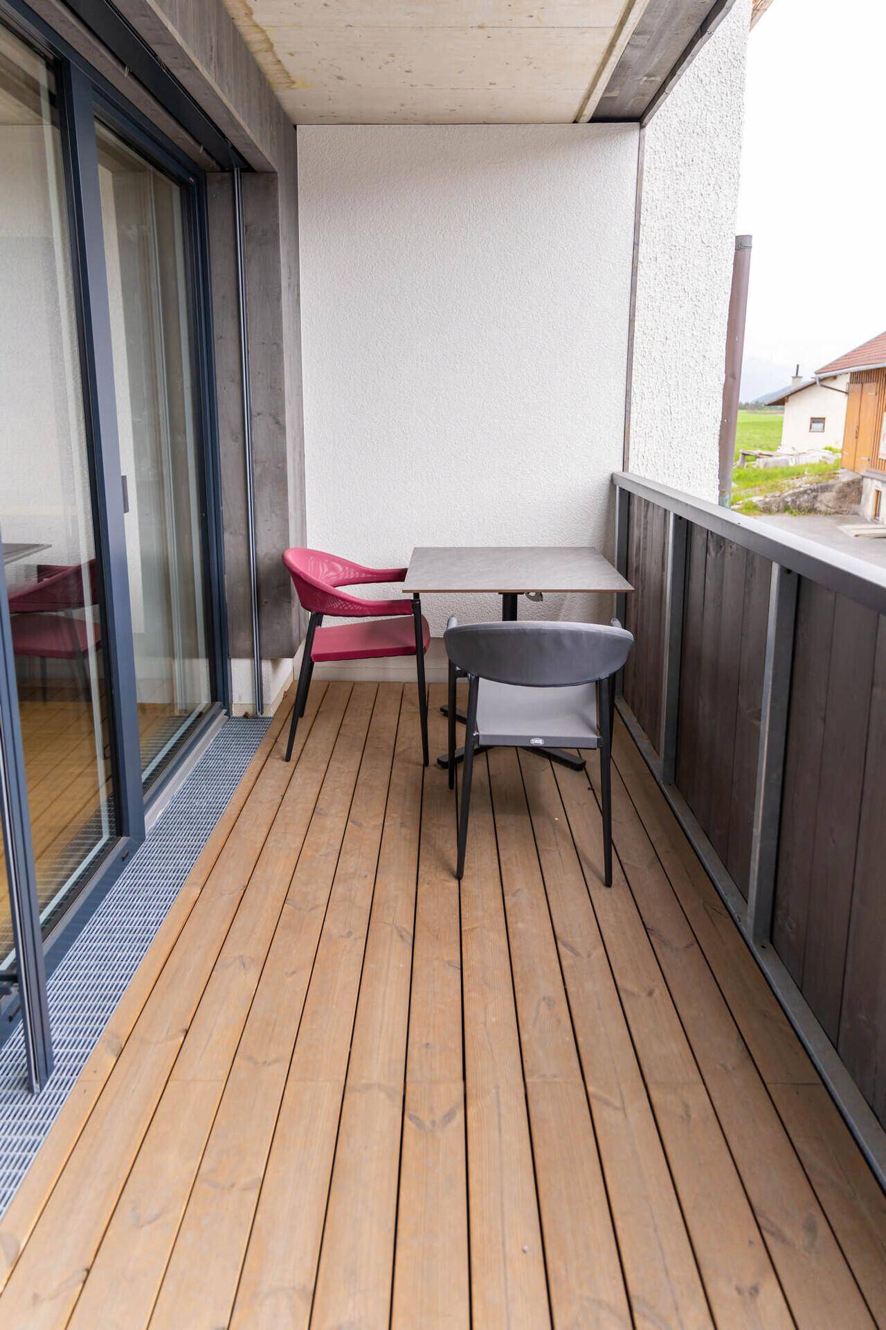 Kleiner Balkon mit Holzboden und Sitzgelegenheiten für entspannte Stunden im Freien.