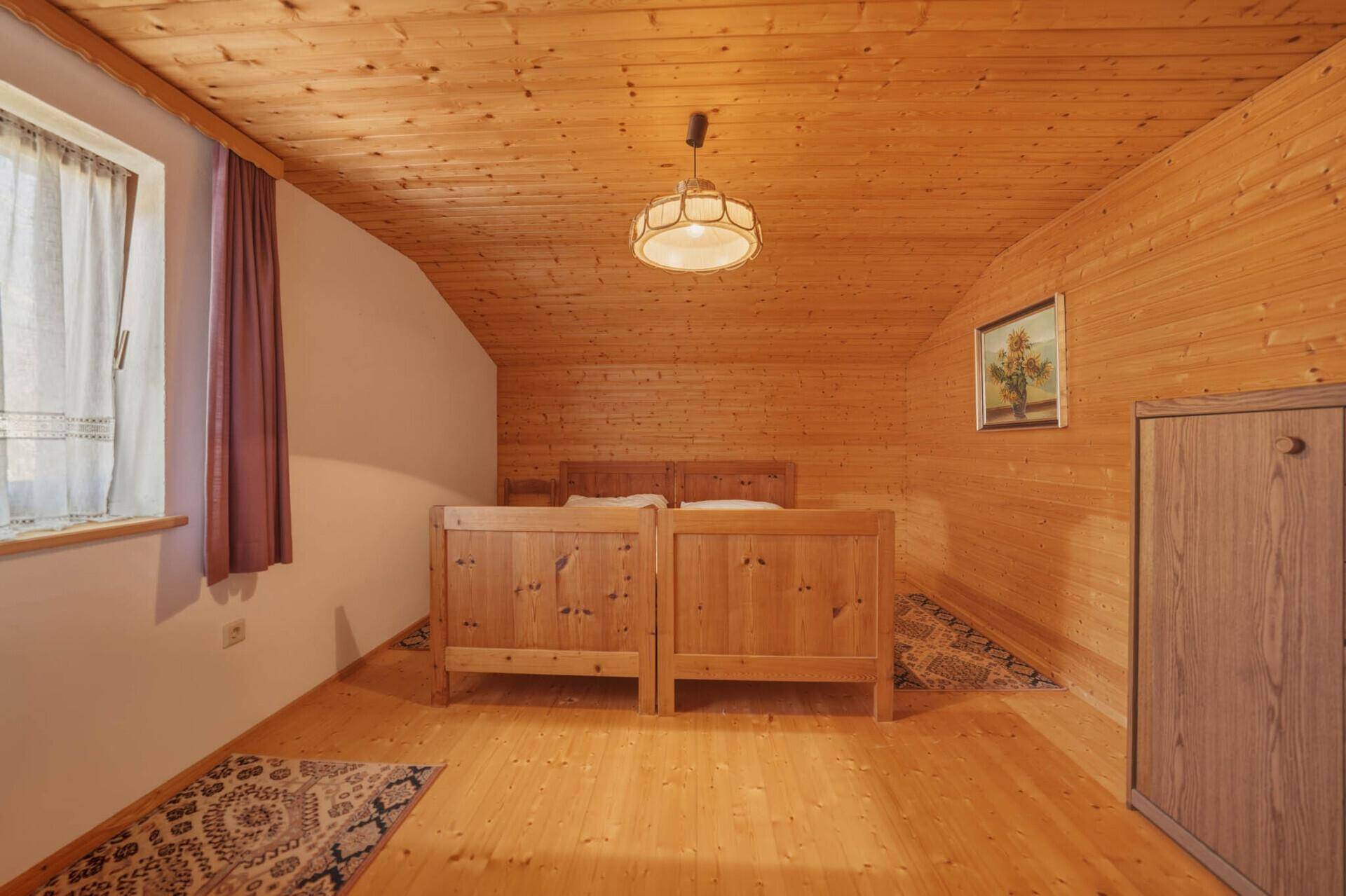 Schlafzimmer im Dachgeschoss mit Holzverkleidung, Einzelbetten und schrägen Wänden.