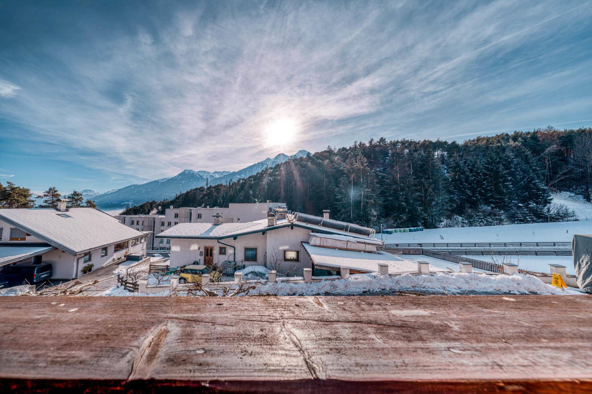 Panoramablick vom Balkon auf die verschneite Landschaft und die umliegenden Berge.