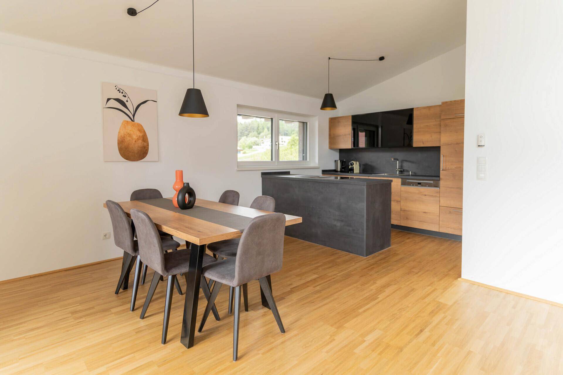 Heller Wohn-Essbereich mit großen Fenstern, Holzboden und Treppenzugang.