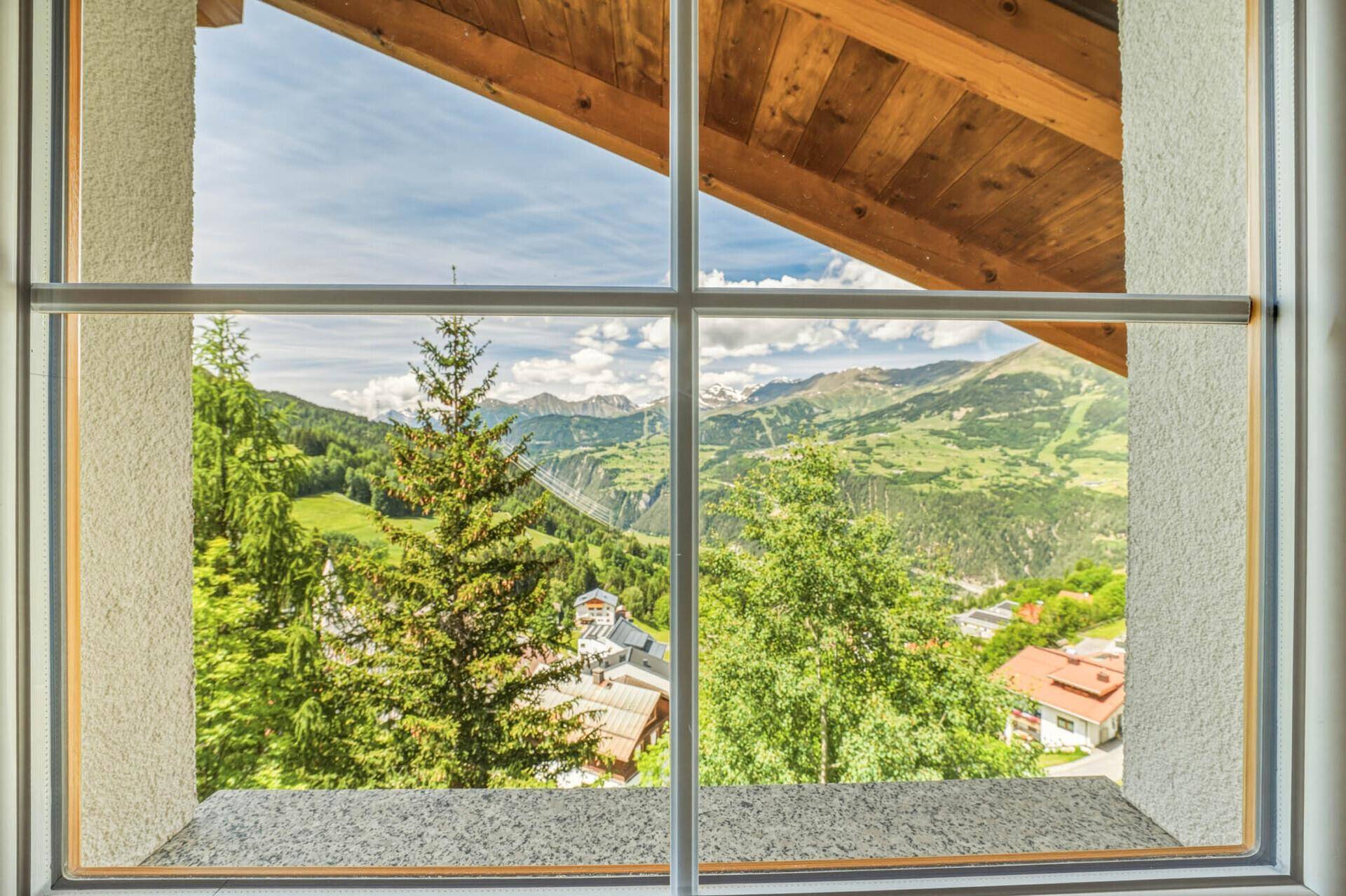 Panoramablick aus dem Fenster auf die umliegende grüne Berglandschaft und das Tal.