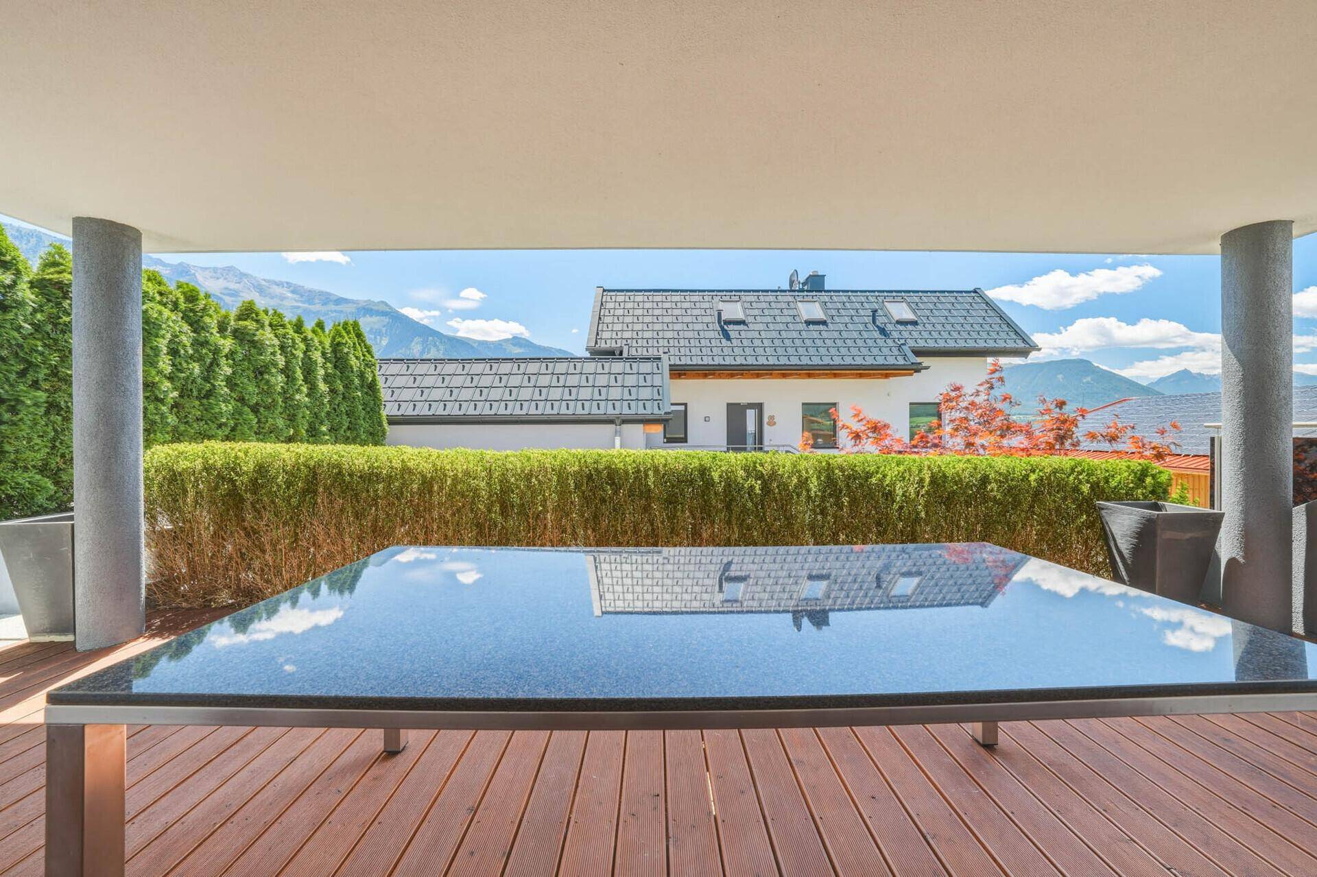 Blick vom Terrassentisch mit Reflexionen des Himmels und einer malerischen Bergkulisse im Hintergrund.
