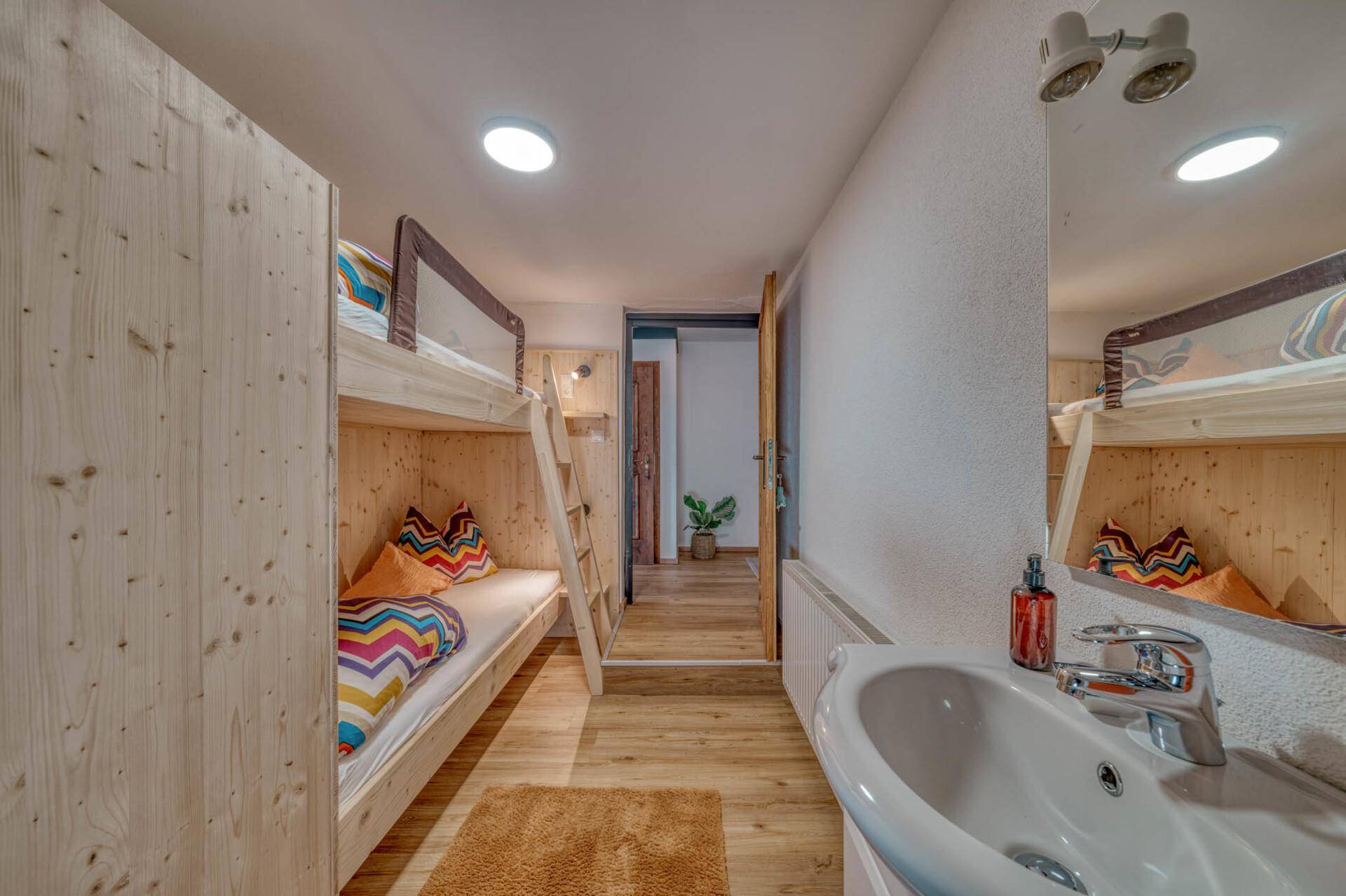 Kinderfreundliches Schlafzimmer mit Etagenbetten, hellem Holzboden und integriertem Waschbecken.