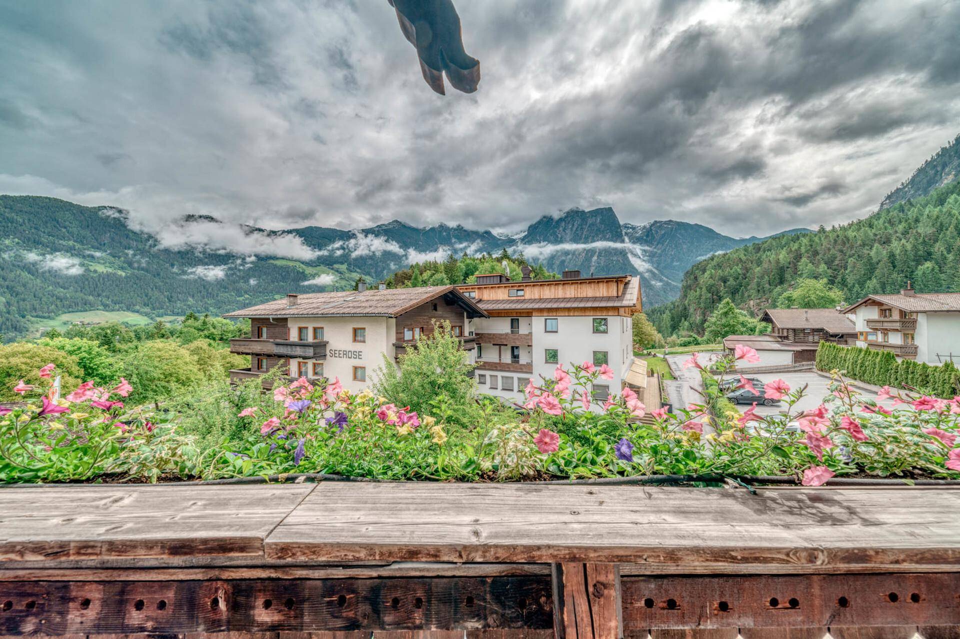 Panoramablick vom Balkon auf eine beeindruckende Berglandschaft und umliegende Gebäude.