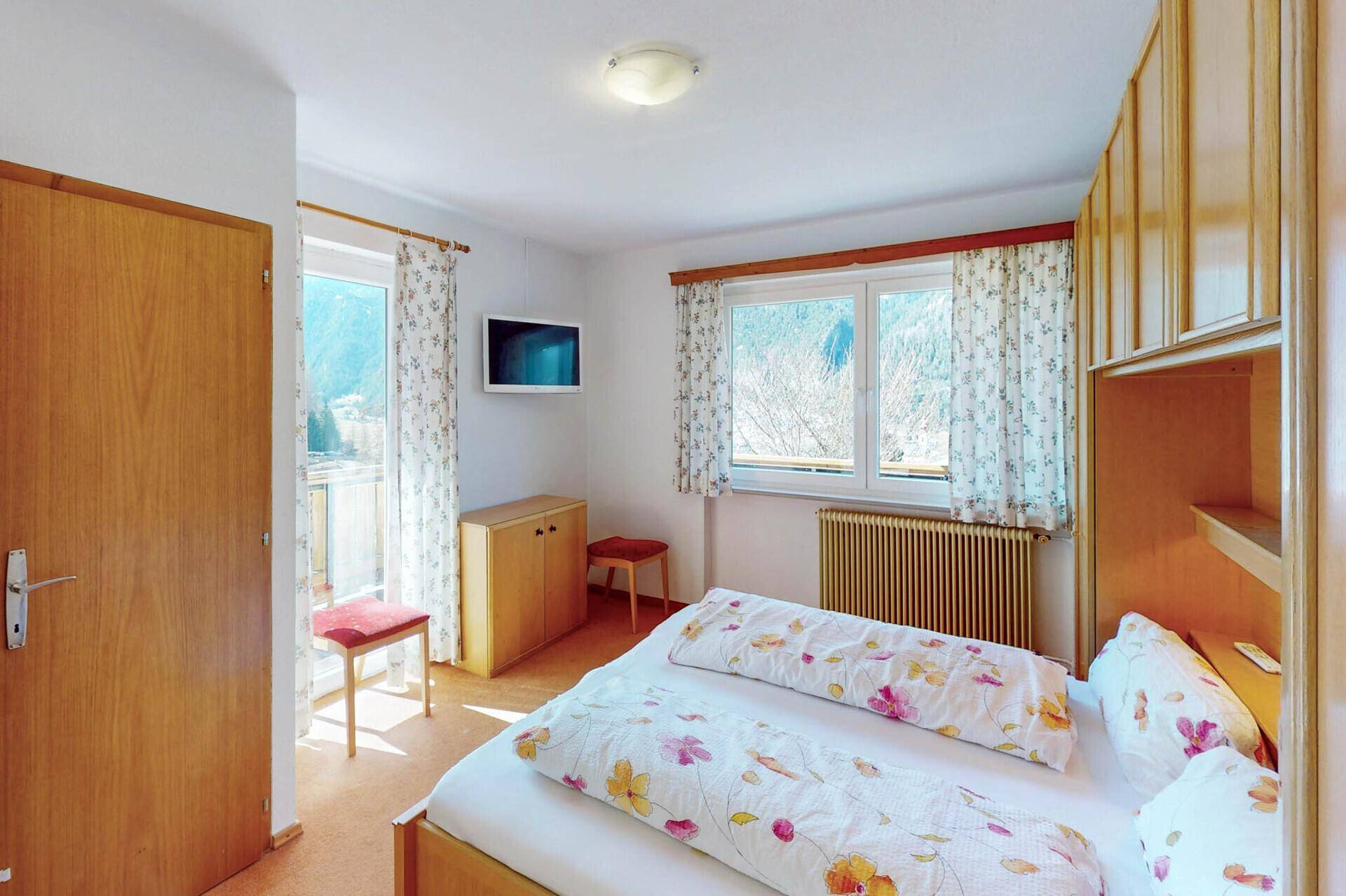 Helles Schlafzimmer mit Doppelbett, Einbauschränken und Balkonzugang.