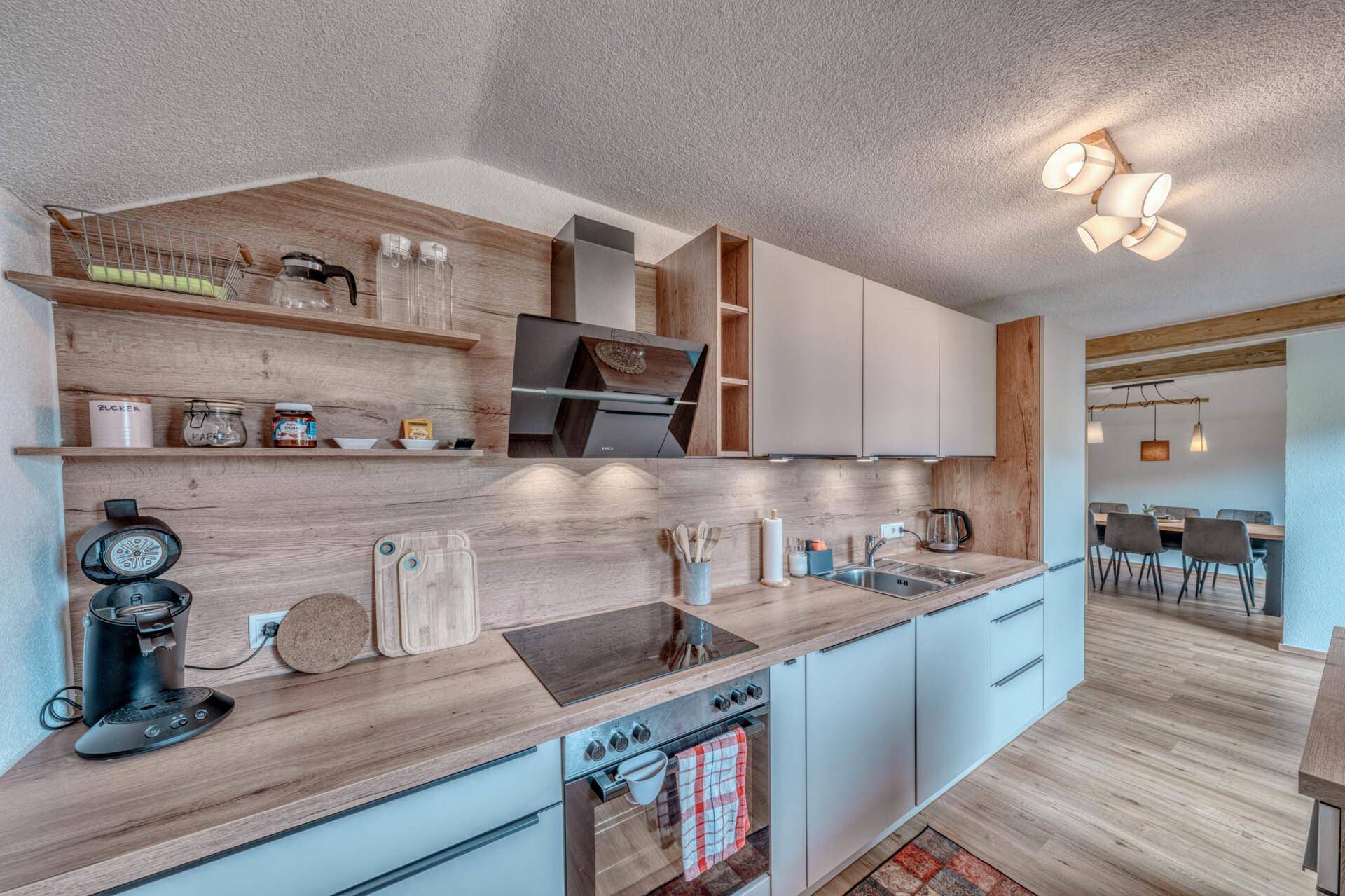Moderne Einbauküche mit hellen Fronten, Holz-Arbeitsplatten und integrierten Geräten.