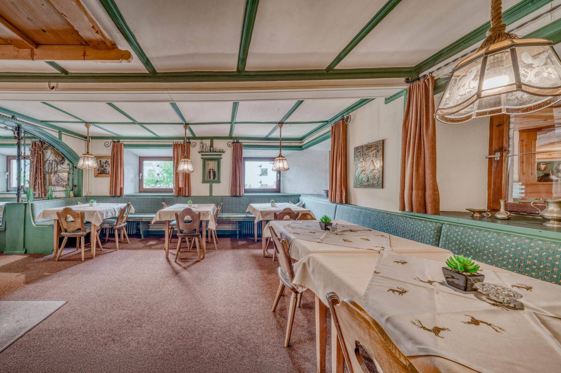 Traditioneller Speisesaal mit grünen Akzenten, Holztischen und gepolsterten Bänken.