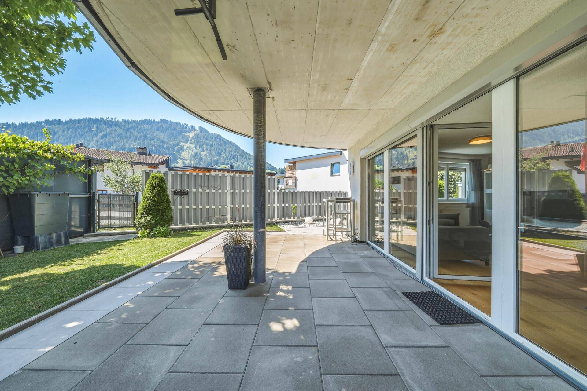 Große gepflasterte Terrasse mit Rasenfläche und Blick auf die Berge.