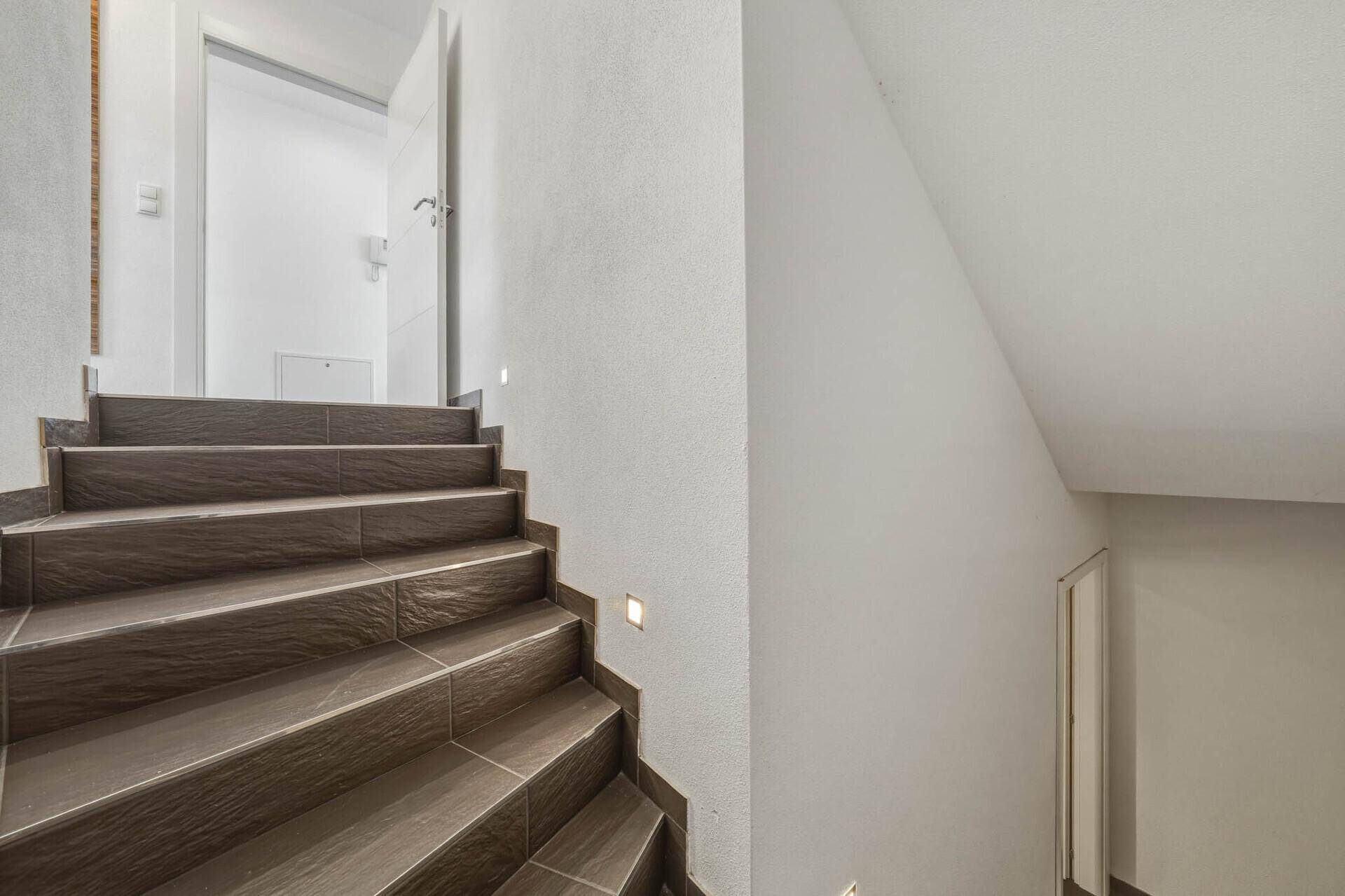 Geflieste Treppe mit indirekter Beleuchtung, die in die obere Etage des Hauses führt.