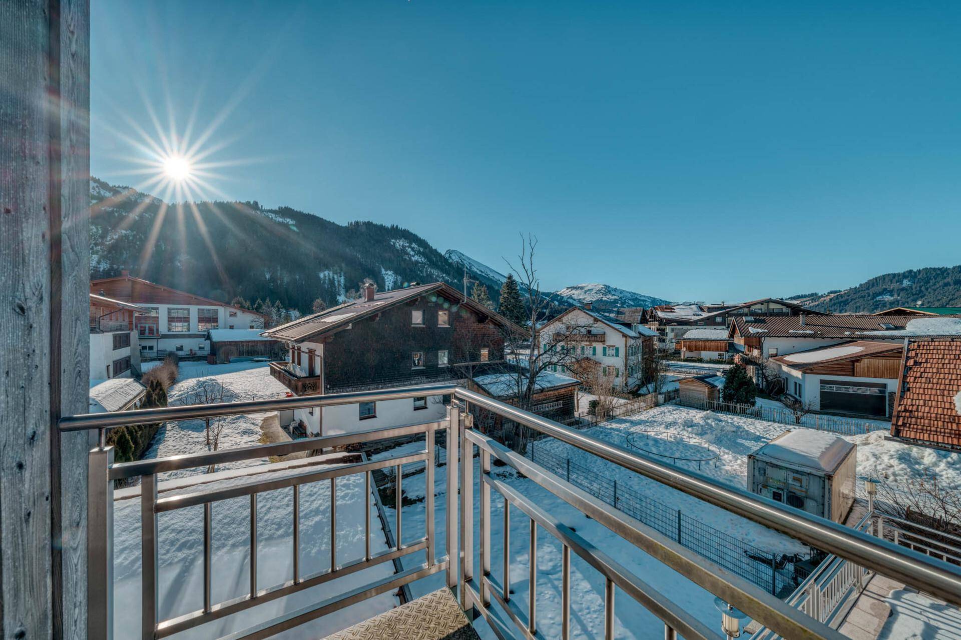 Sonniger Balkon mit Edelstahlgeländer und freiem Blick auf die verschneite Umgebung.